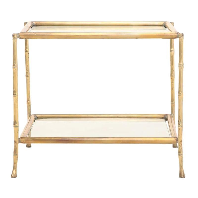 A pair of gilt faux bamboo metal side tables in the style of Maison Bagues.  Crafted in the 1940's, the two tier, square tables have a glass top and glass shelf below.  A chic addition that adds glamour and style to any living space.