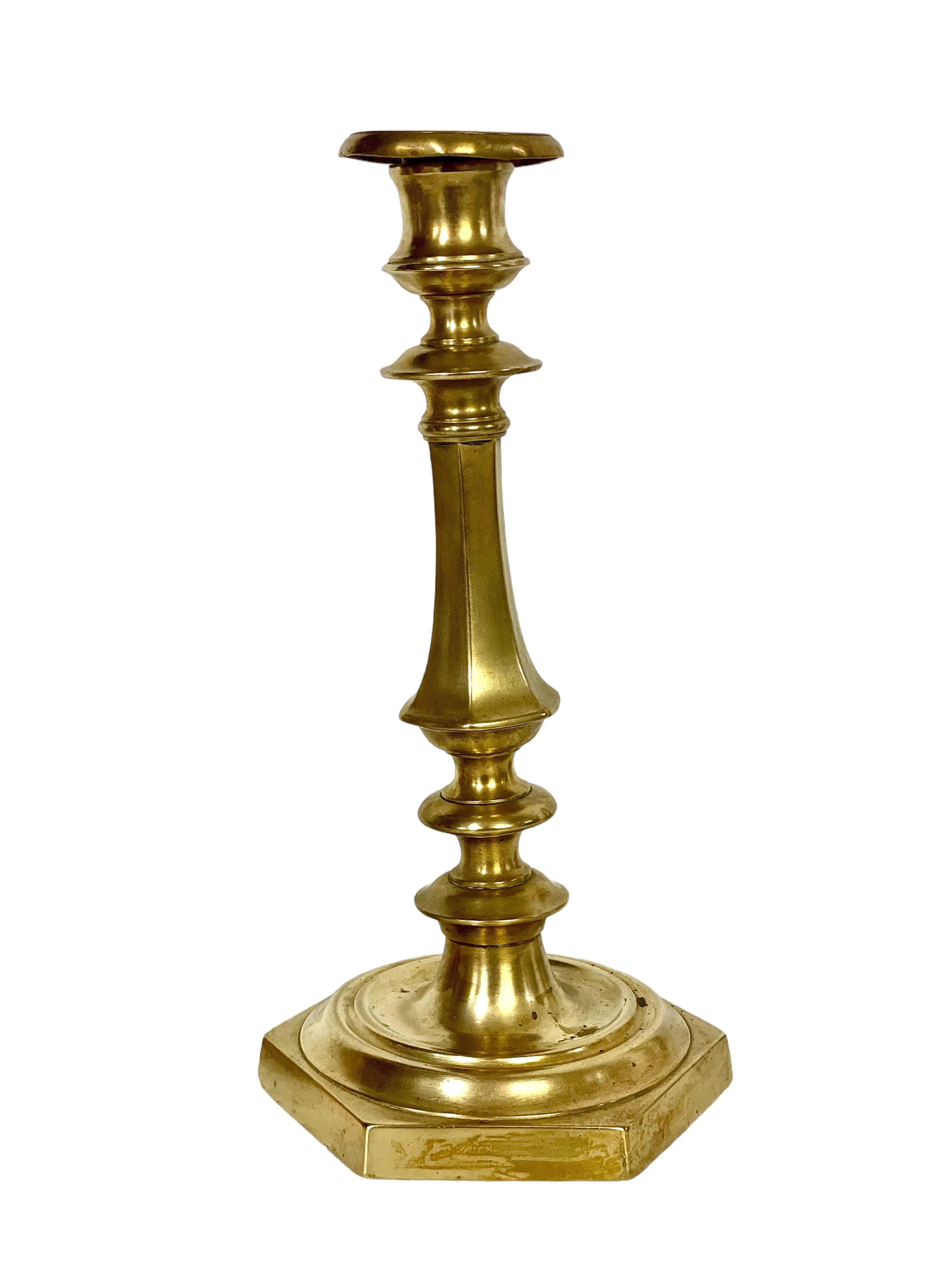 A fine pair of French “Flambeaux” gilt bronze candlesticks, dating from the 19th century, and crafted in a traditional baluster form. Rising from a heavy hexagonal base, each one has a turned, shaped and knopped stem, terminating in a simple but