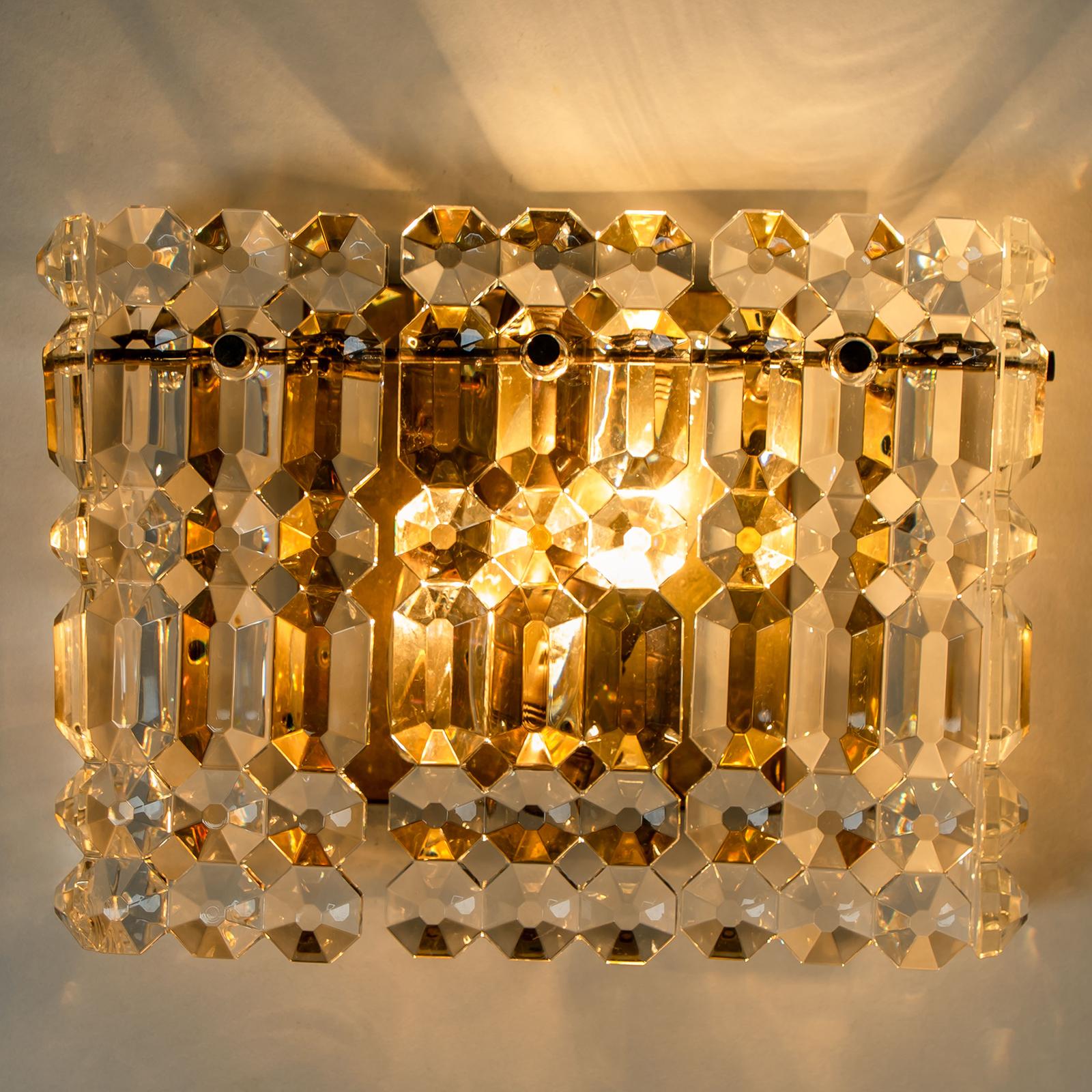 A luxurious pair of gold-plated frames and thick crystal sconces by the famed maker, Kinkeldey. Two-light sources. Very elegant light fixtures, comfortable with all decor periods. The crystals are meticulously cut in such a way that radiate the