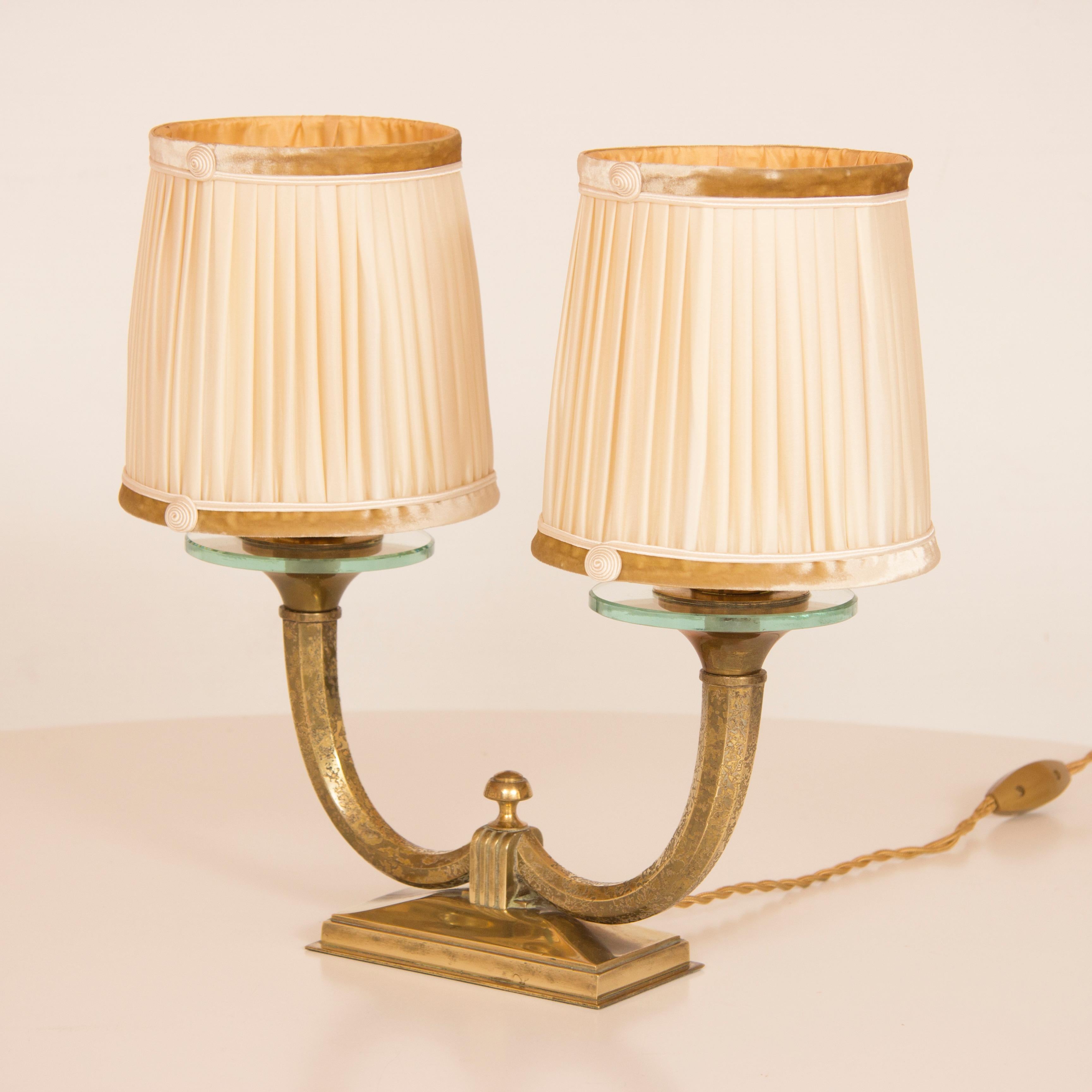 A fine pair of table lamps with original pleated silk shades trimmed with a button swirl on a crushed velvet band.
Gilt bronze base with acid flocked gilt bronze arms with thick glass disk below the shades.
both signed Genet and Michon at the wire