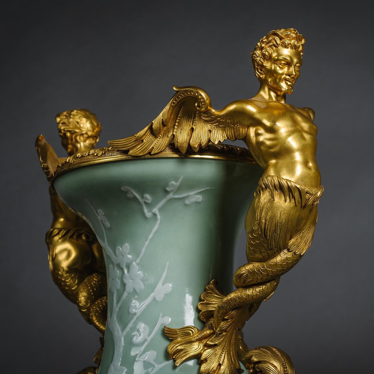 A Pair of Large Gilt-Bronze Mounted Chinese Celadon-Ground and Slip Decorated Porcelain Vases.

These vases of Chinese celadon porcelain from the late Quing Dynasty are slip-decorated with willow trees and prunus flowers. The finely sculpted