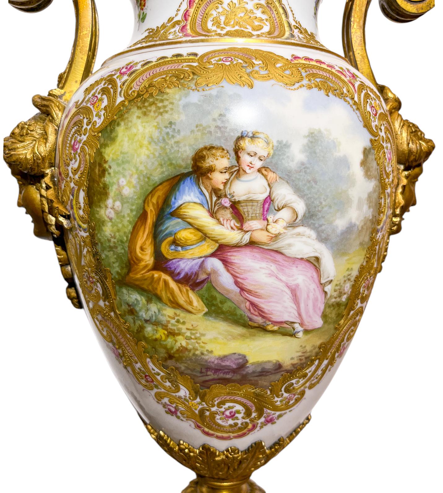 Coppia di urne in porcellana di Sèvres montate su bronzo dorato con scene di corteggiamento e paesaggi pastorali dipinte sul retro da L.Bertren. Incorniciati da una cornice policroma dipinta in rilievo e dorata, la coppia è sormontata da terminali a