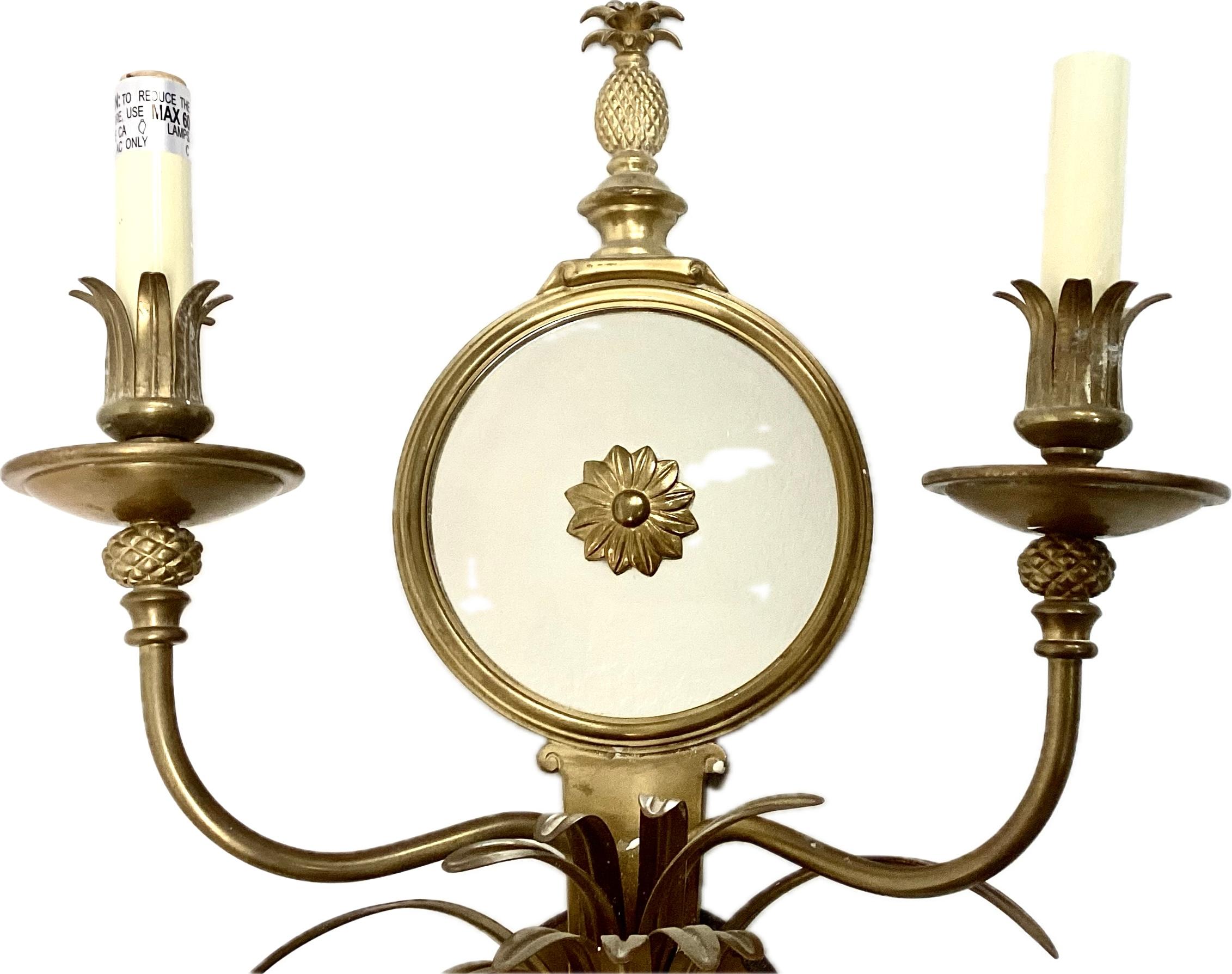 Coppia di applique in bronzo dorato francese del XX secolo con specchi rotondi Antique Mirror. Ogni applique presenta due bracci curvi progettati per ospitare lampadine a candela, che possono illuminare una stanza con una luce d'ambiente morbida. La