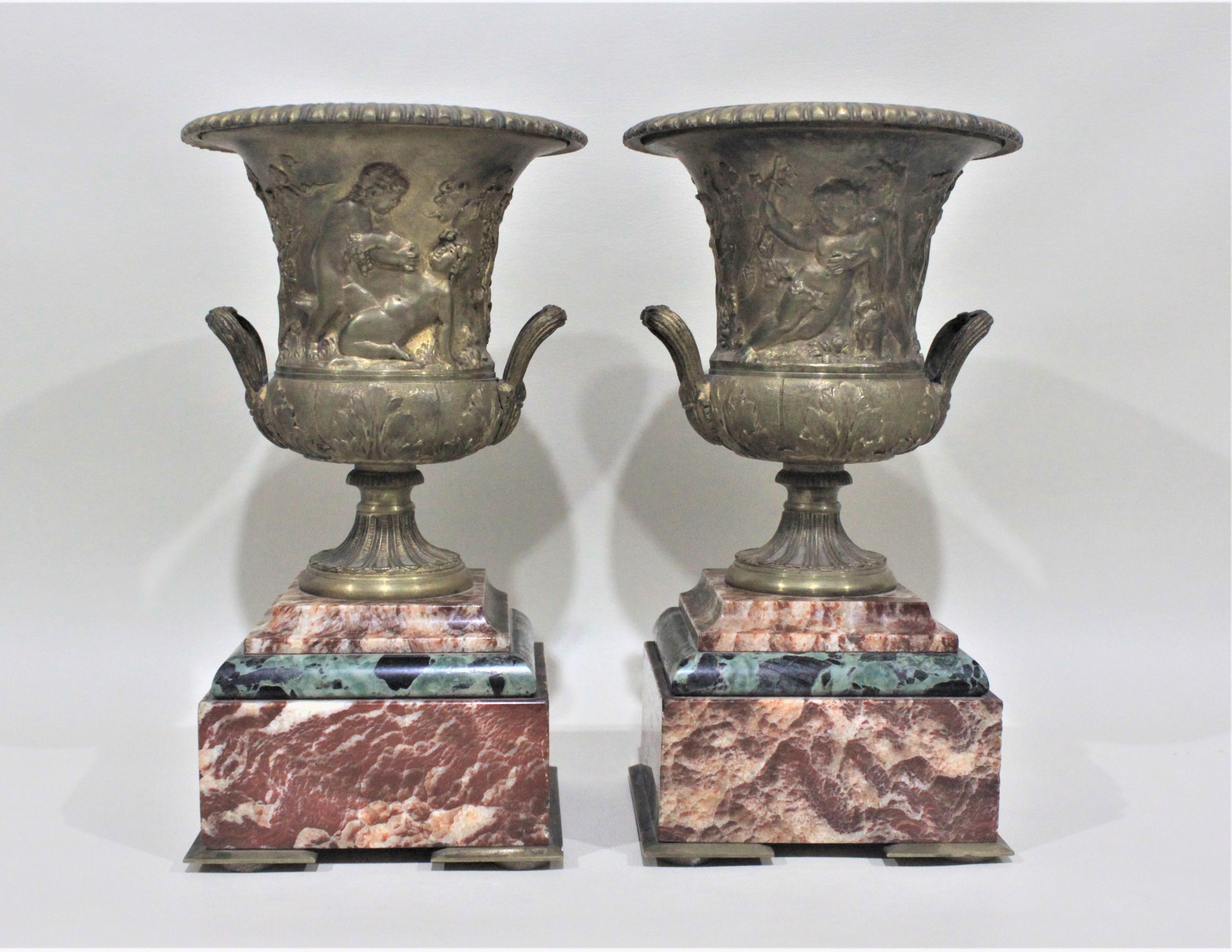 Questa coppia di urne in bronzo dorato e marmo è ornata da un motivo neoclassico sia sul fronte che sul retro e poggia su una base di lastre di marmo rosa e nero alternate. Questa coppia di urne abbinate risale probabilmente al periodo vittoriano ed
