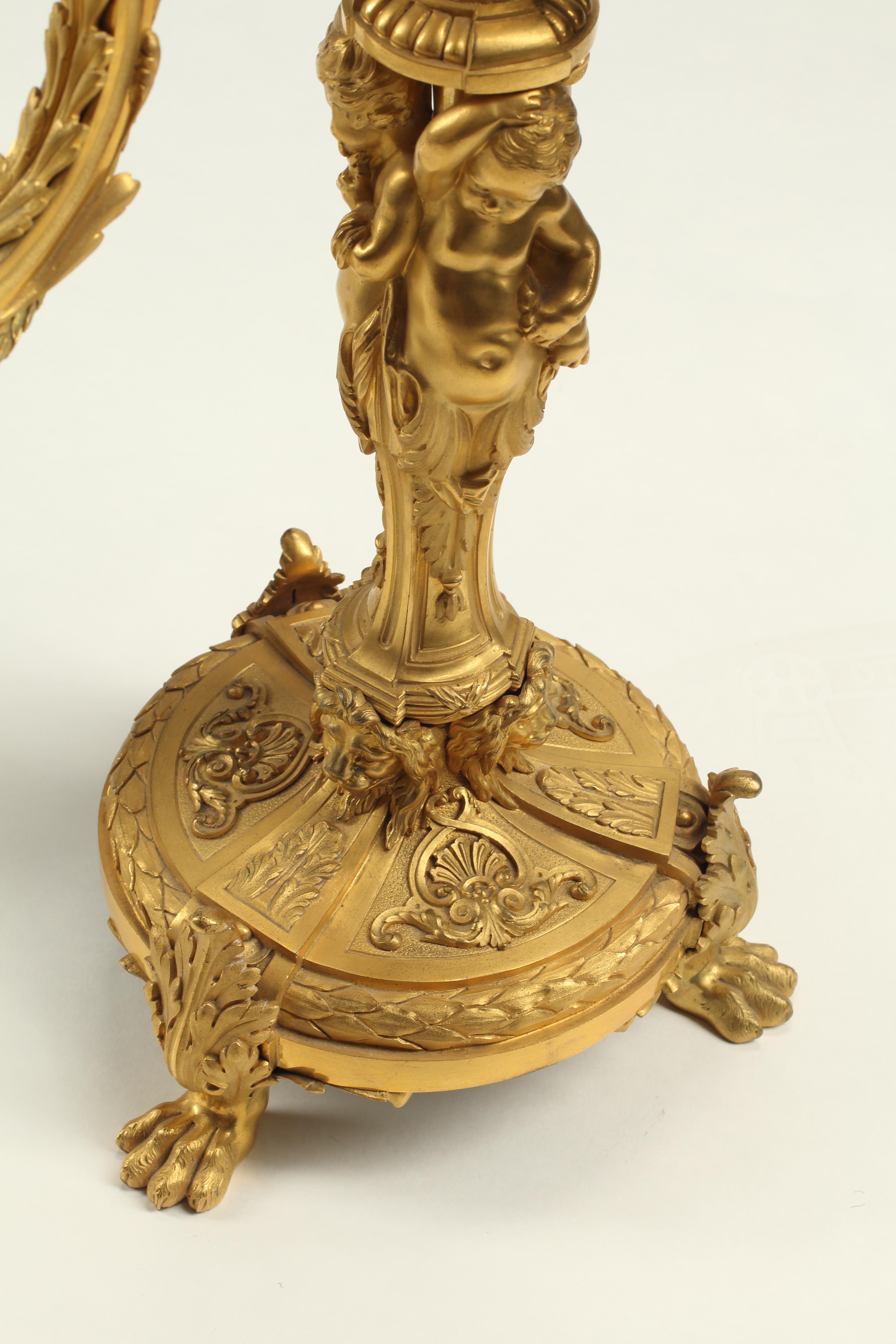 Una sensazionale coppia di candelabri a tre luci in bronzo dorato in stile Luigi XV del XIX secolo, con dettagli e maestria impeccabili. Ogni candelabro vanta uno stelo centrale con figure di puttini che sorreggono un piedistallo ornato da foglie