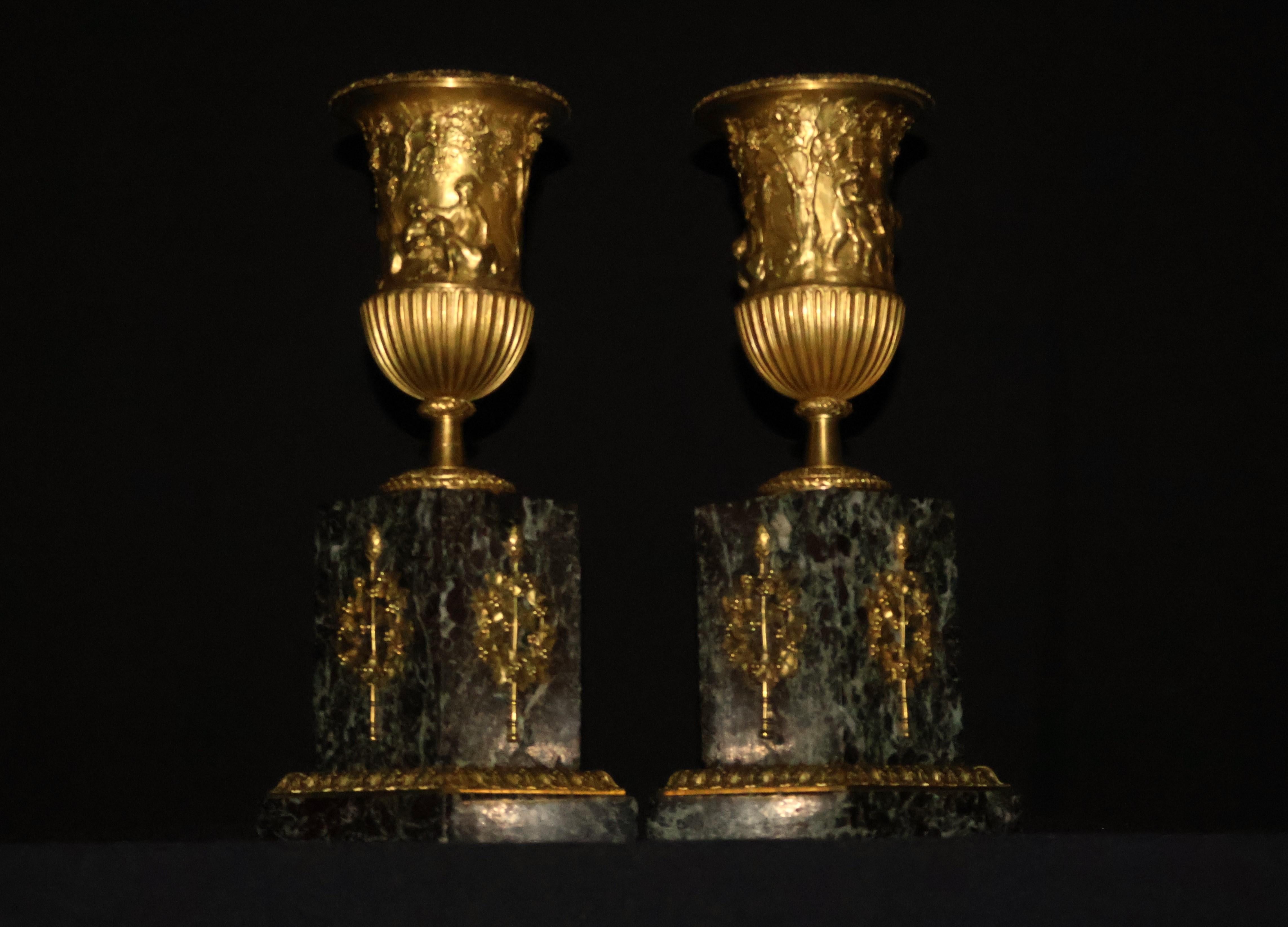 Empire Pair of gilt bronze urns raised on a marble plinth with ormolu mounts.  For Sale