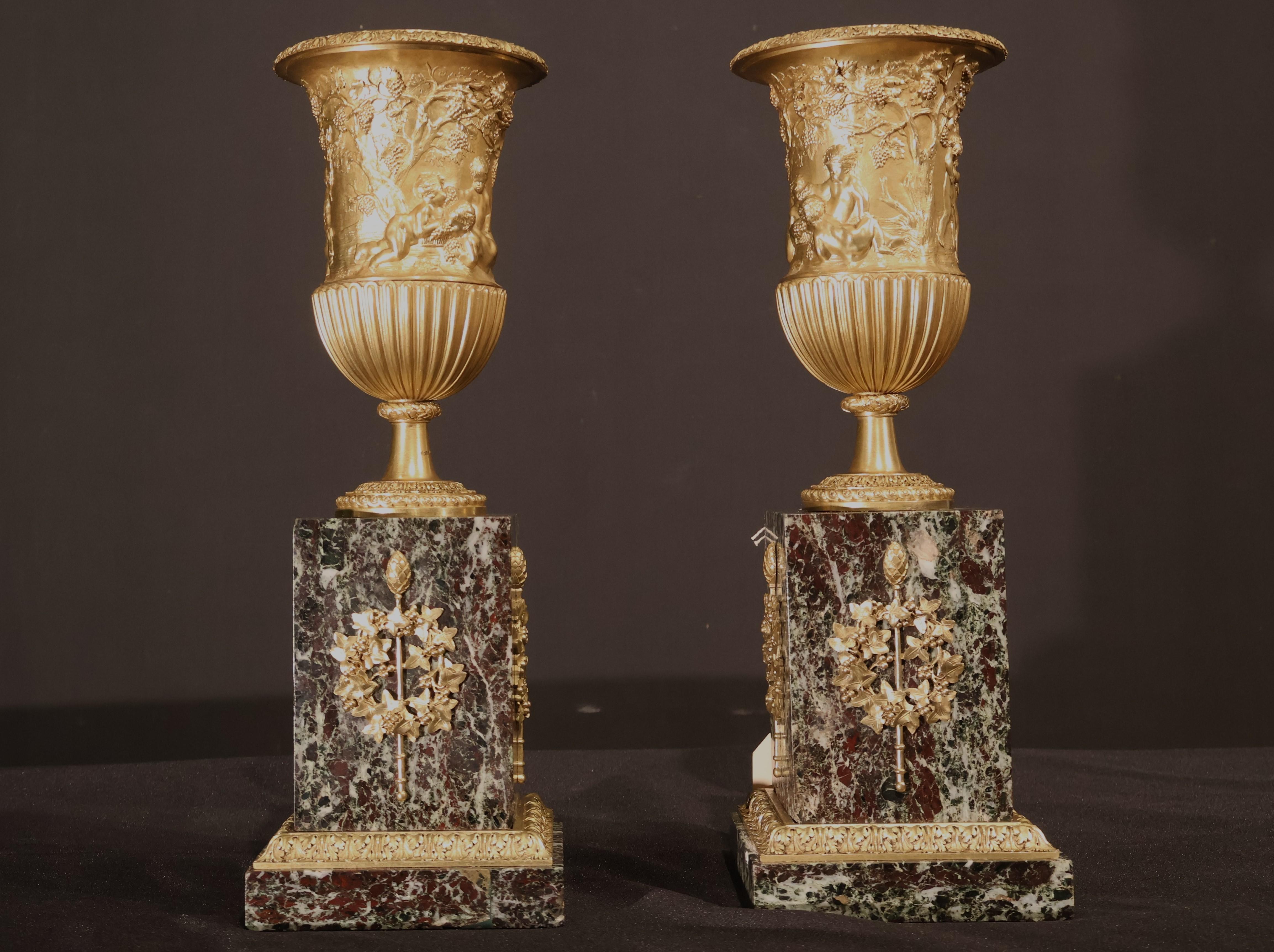 French Pair of gilt bronze urns raised on a marble plinth with ormolu mounts.  For Sale