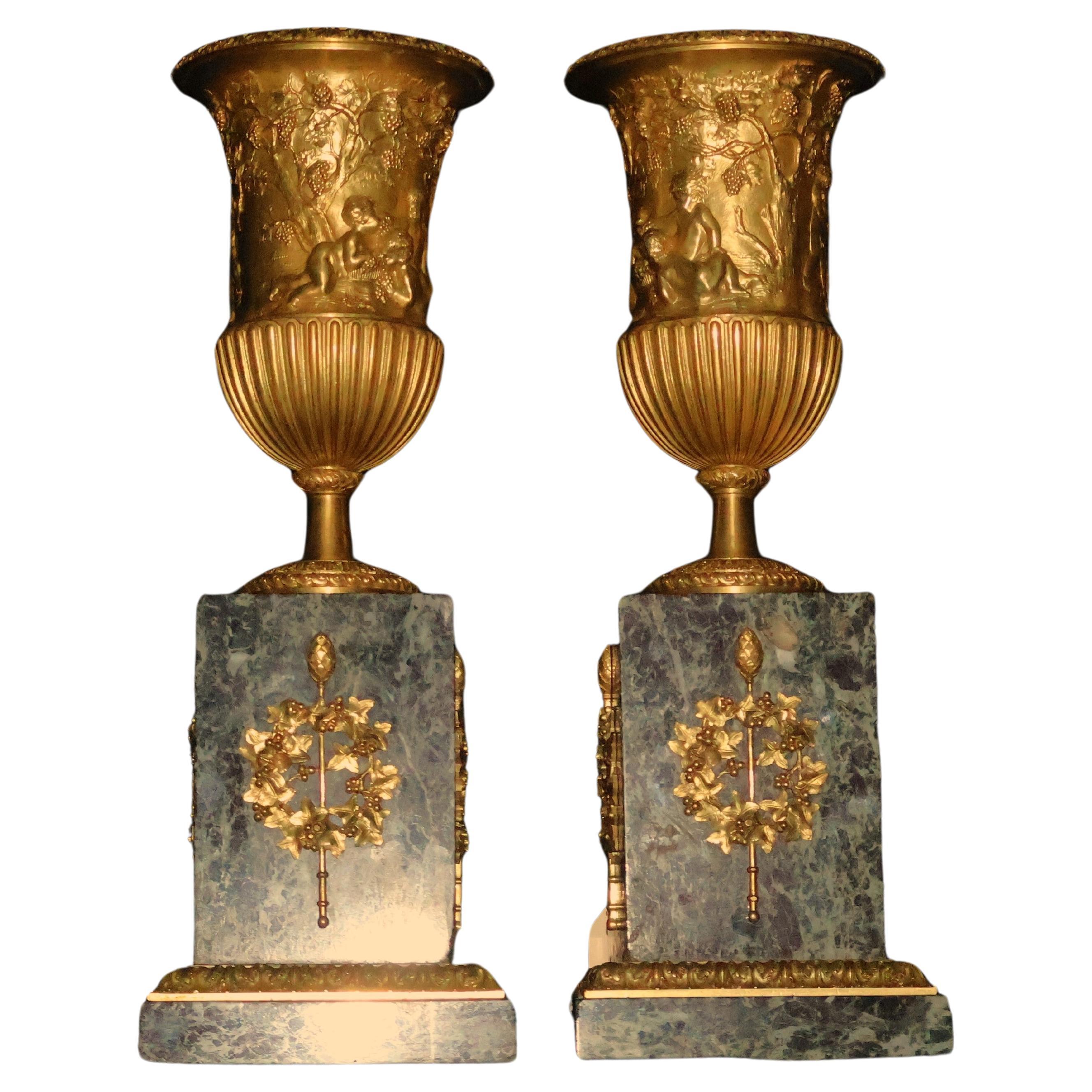 Pair of gilt bronze urns raised on a marble plinth with ormolu mounts.  For Sale