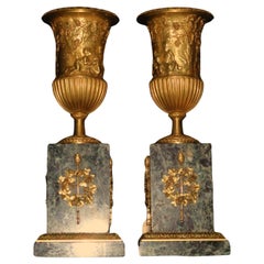 Pair of gilt bronze urns raised on a marble plinth with ormolu mounts. 