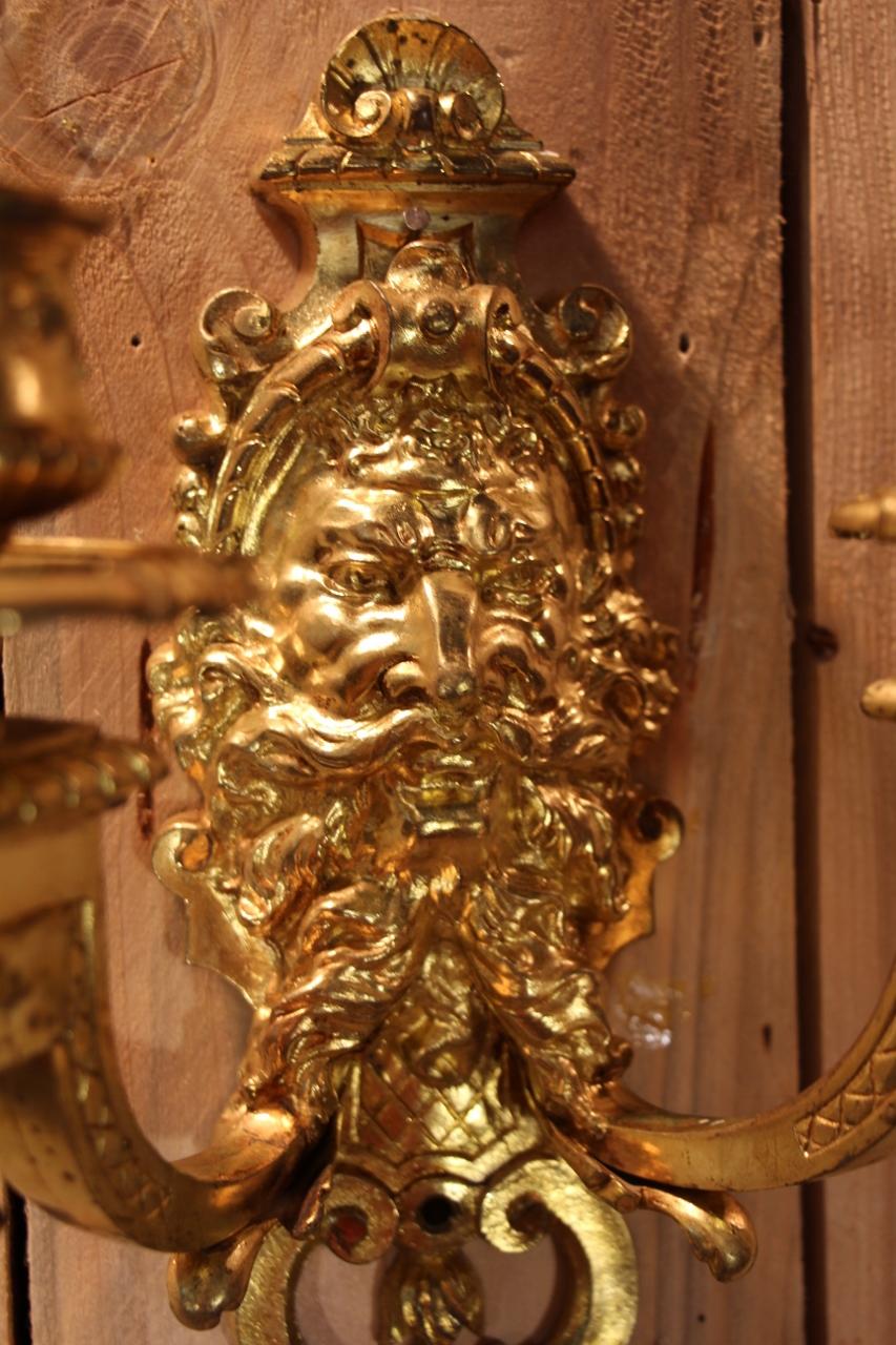 Pair of gilt bronze wall lights with two light arms decorated with a mascaron, mid-19th century, Regency style