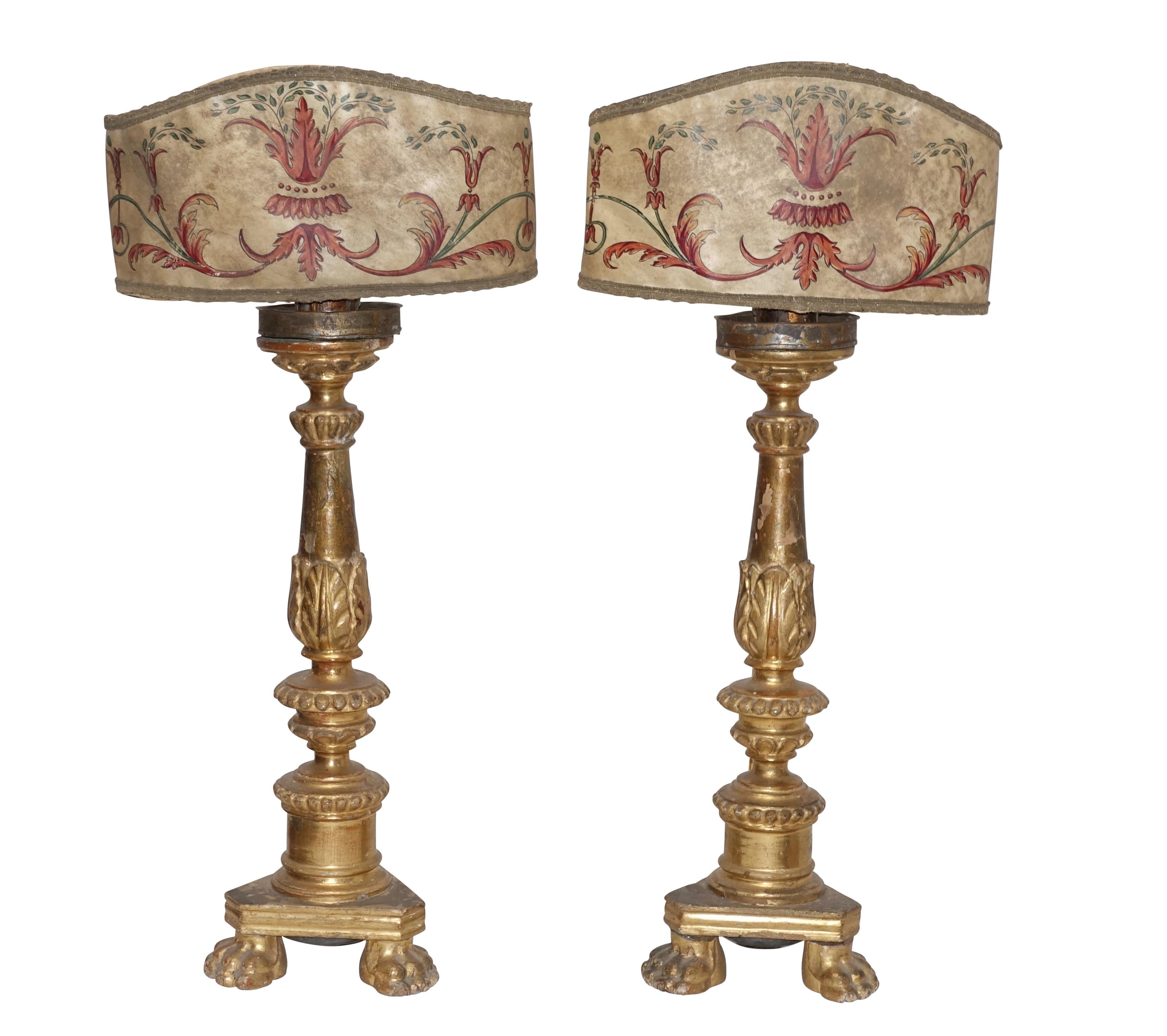 Pair of carved wood and gilt candlesticks now converted to lamps with clip-on hand painted parchment lamp shades, Italian, 18th century.
