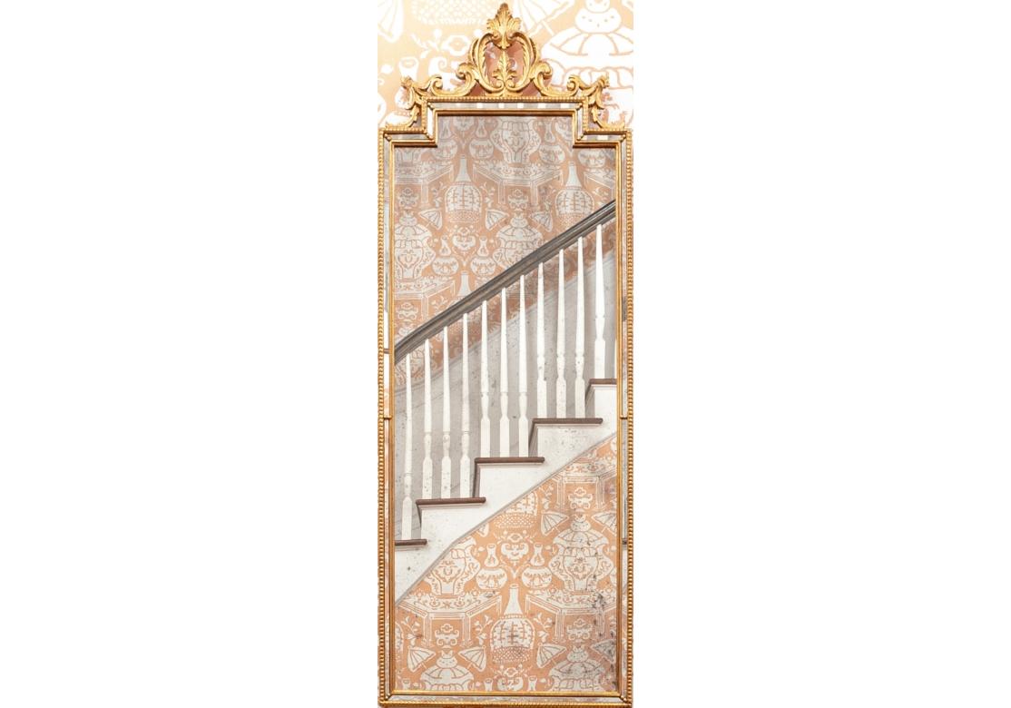 A pair of highly decorative gilt Italian rectangular wall mirrors with a graceful pieced accent crowning their generous height. The mirrors with a 1/2