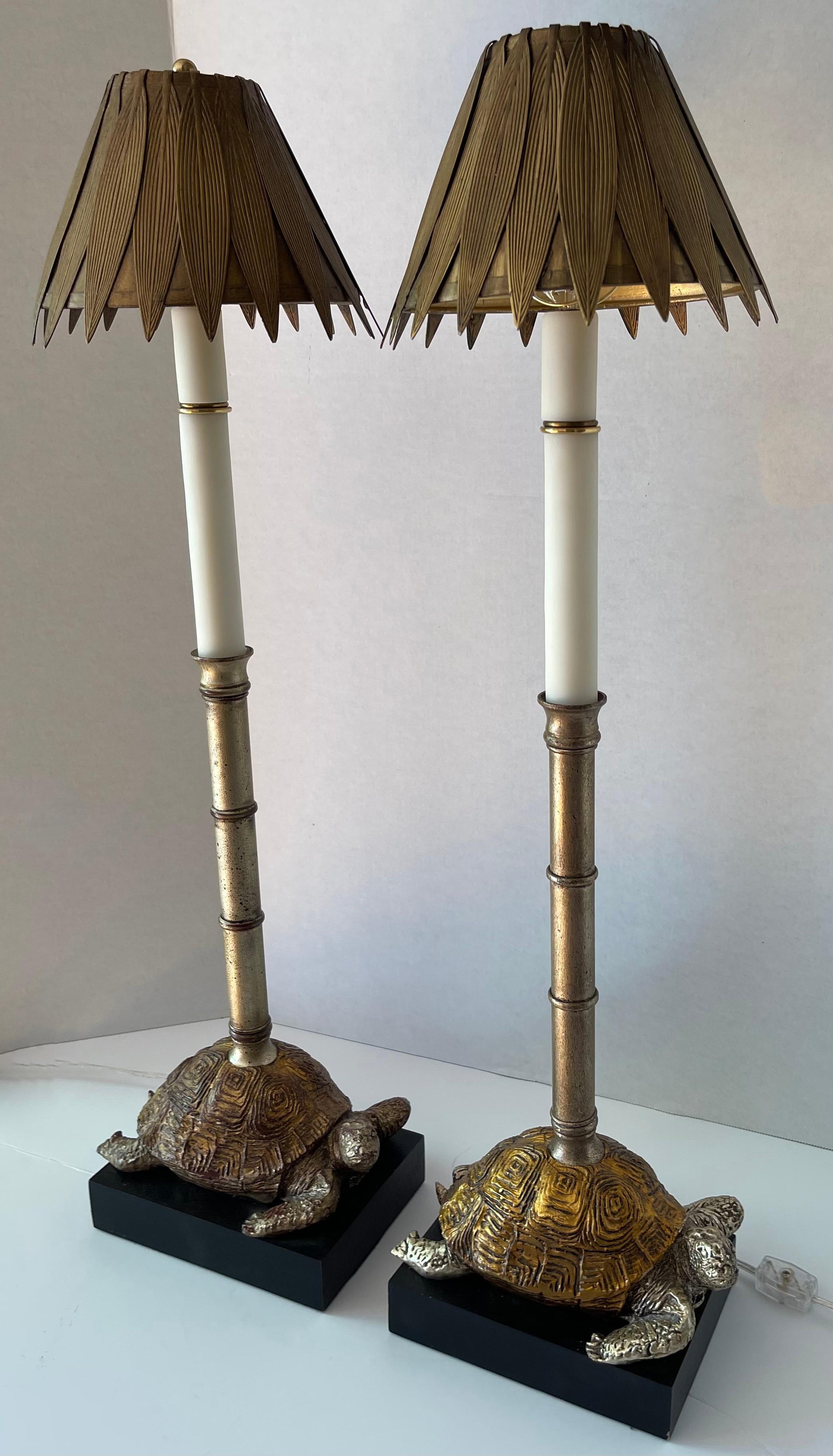 Coppia di lampade da buffet alte in finto bambù dorato.
Base in legno dipinta di nero con attaccata una base di tartarughe in gesso dorato. Corpo in finto bambù in metallo dorato/argento.

Cablata di recente con Corde chiare e interruttori laterali.