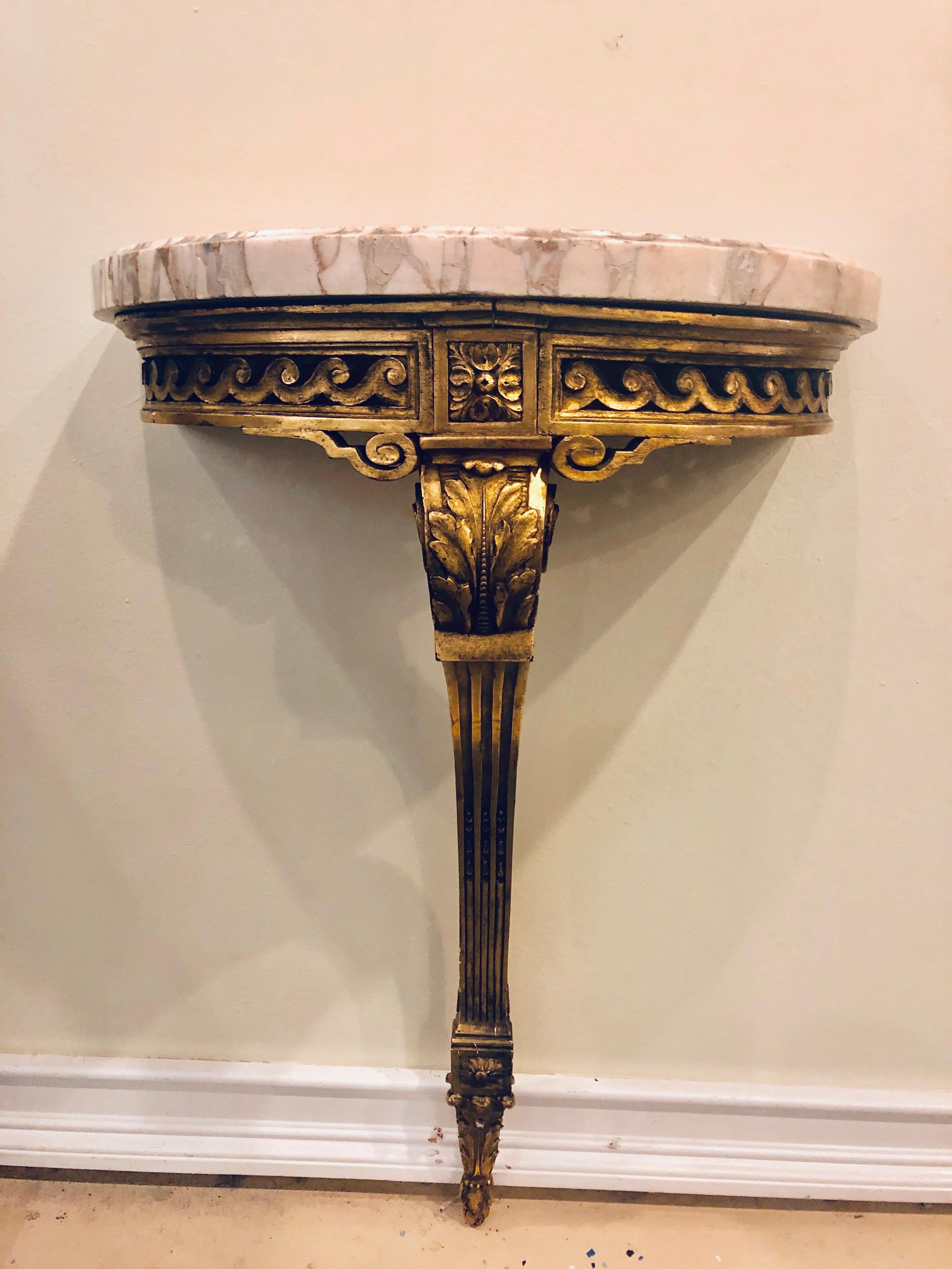 Pair of gilt gold Louis XVI Maison Jansen wall mount Demilune console tables. Each antique gilt wooden console table of Demilune form with pierced carved aprons leading to a center carved S-shaped leg. The whole supporting an antique marble top that