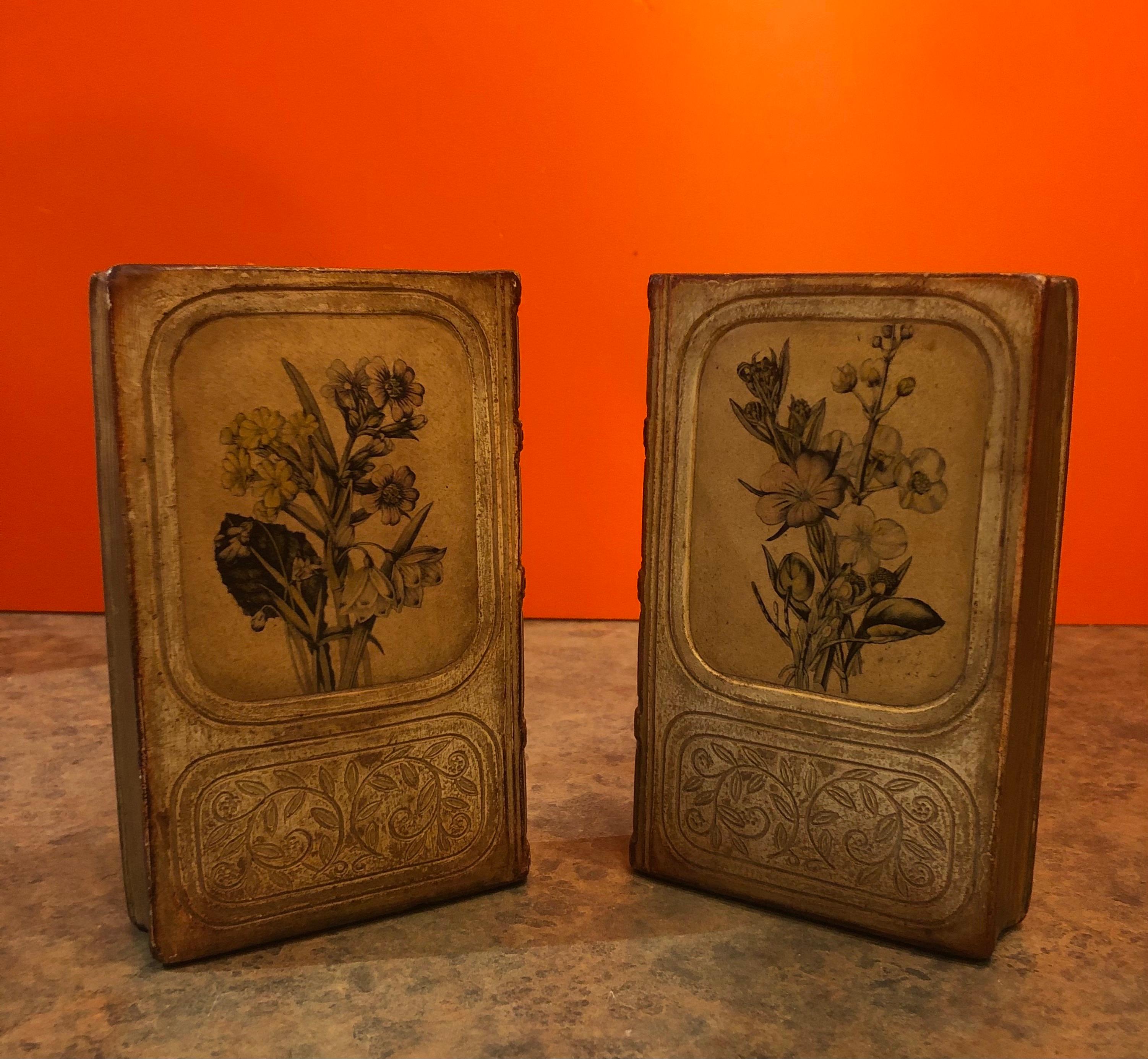 Nice pair of Hollywood Regency bookends in a gold gilt finish in the shape of books with a floral cover jacket by Borghese of Italy, circa 1960s. The pair are in good vintage condition and measure 6