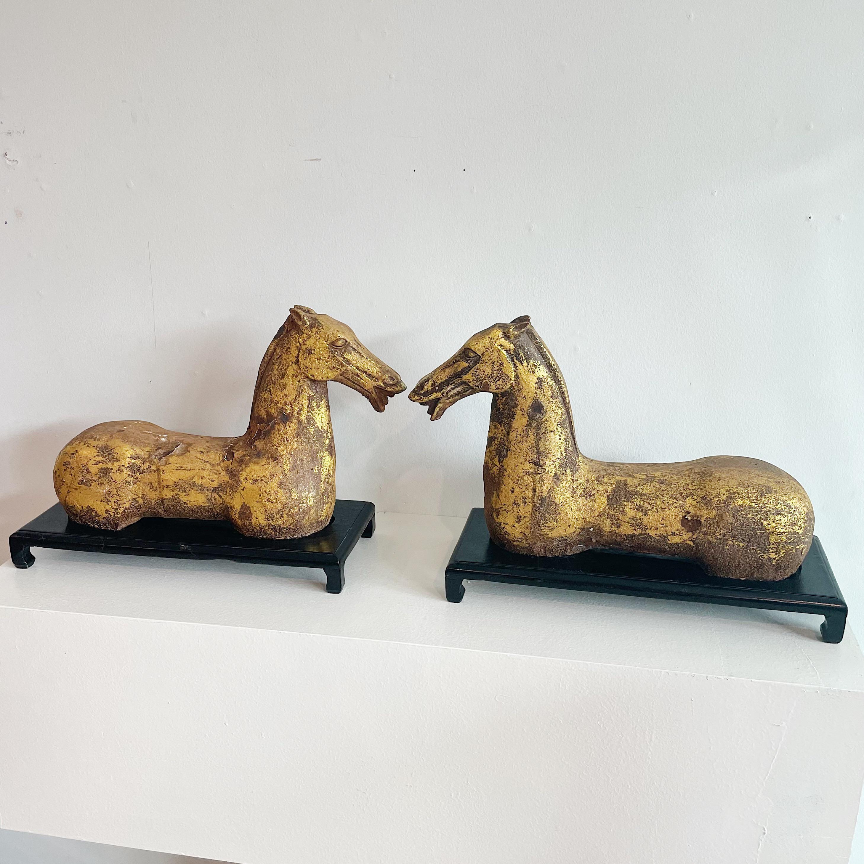 Vintage pair of heavy gold leaf over iron Chinese Han Dynasty style Horses on black lacquered wood bases. Heavily worn.