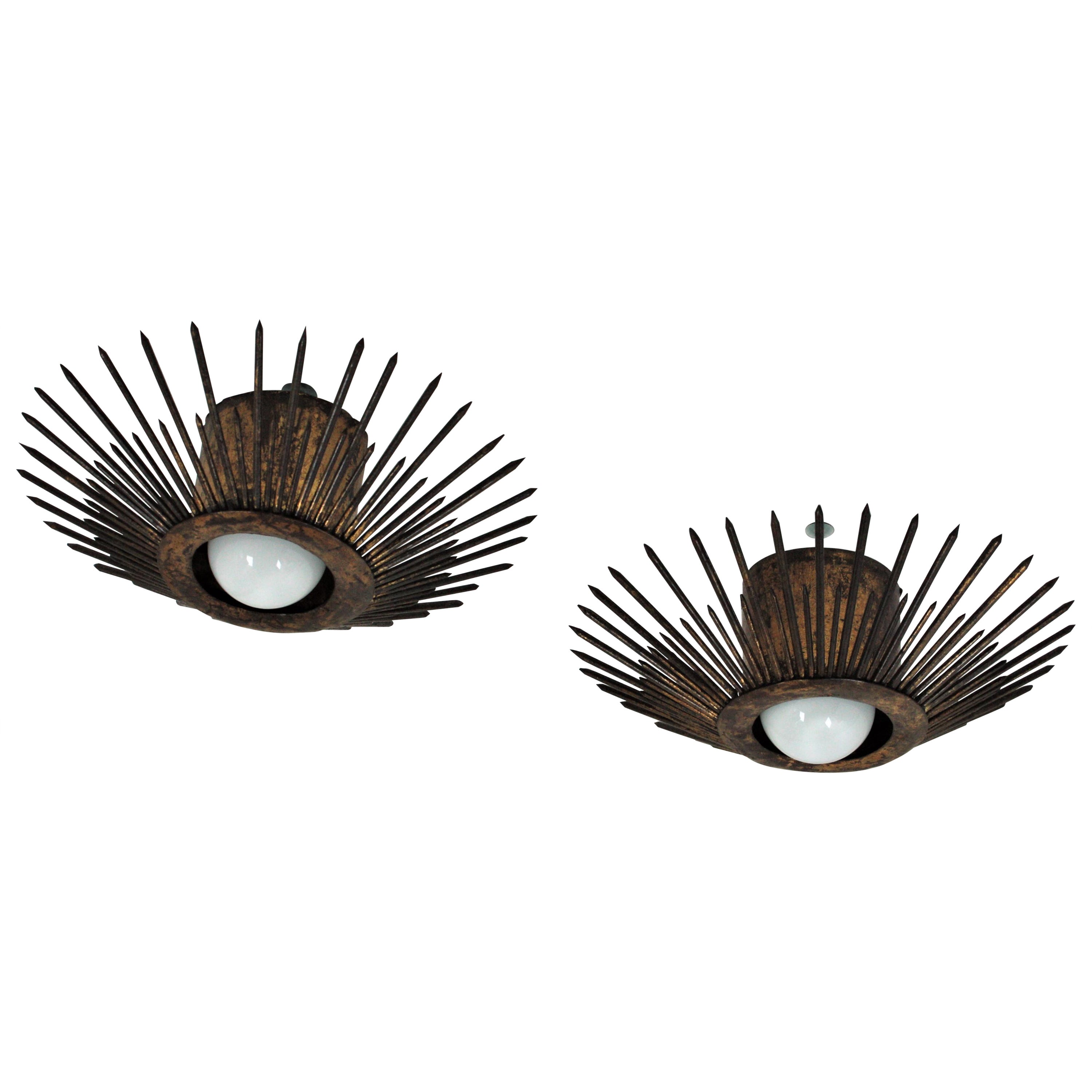 Terrific pair of wrought iron sunburst flush mounts with spikes design and parcel-gilt finish. France, 1940s.
These eye-catching sunburst ceiling lights have a strong design with pointed spikes in sunburst disposition. They have two layers of iron