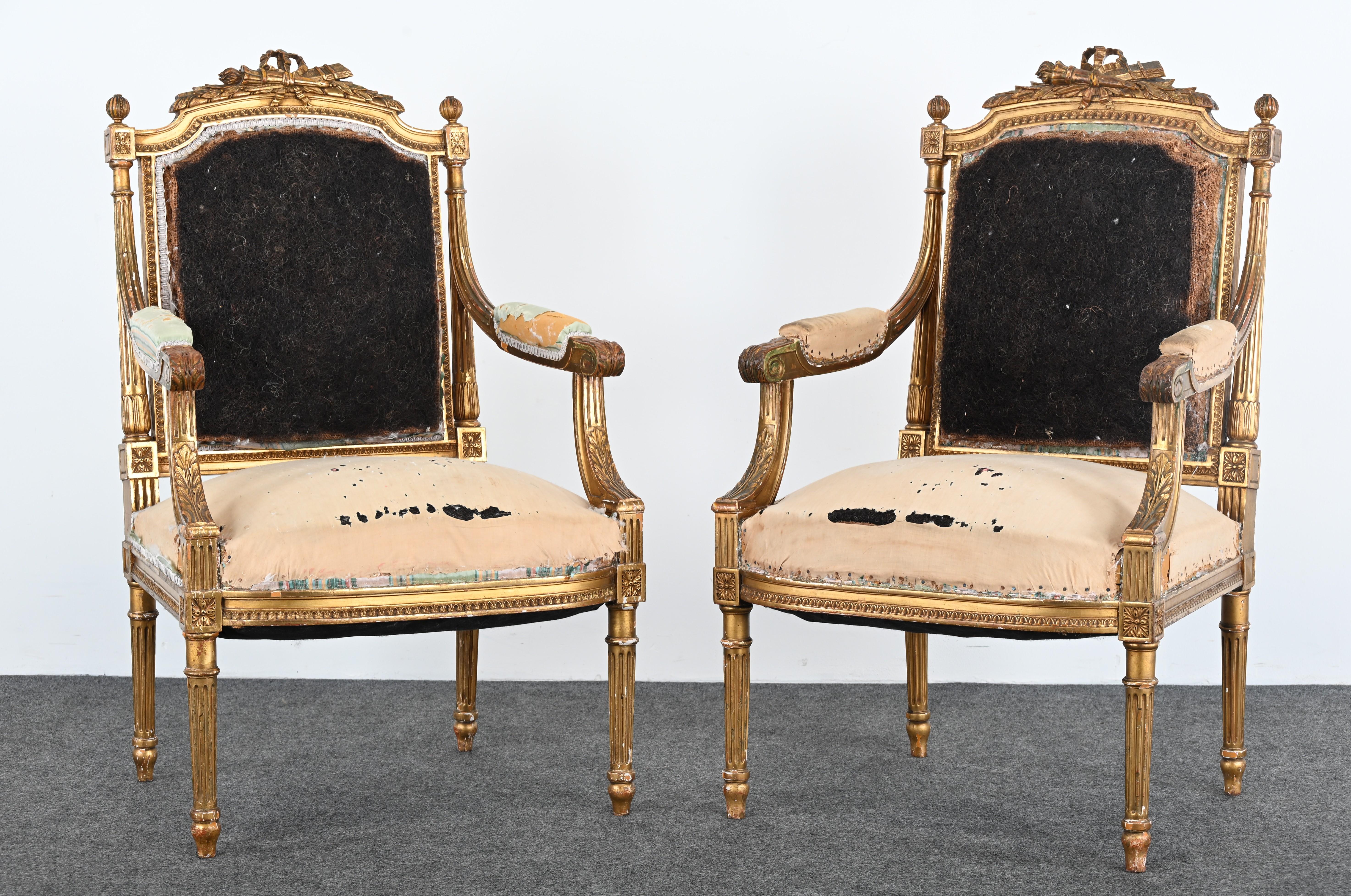 This exquisite pair of gilt Louis XVI French chairs, circa 1900, showcases the timeless elegance of neoclassical design. Crafted with a finely detailed giltwood frame, each chair features ornate carvings, including floral motifs and ribbon accents,