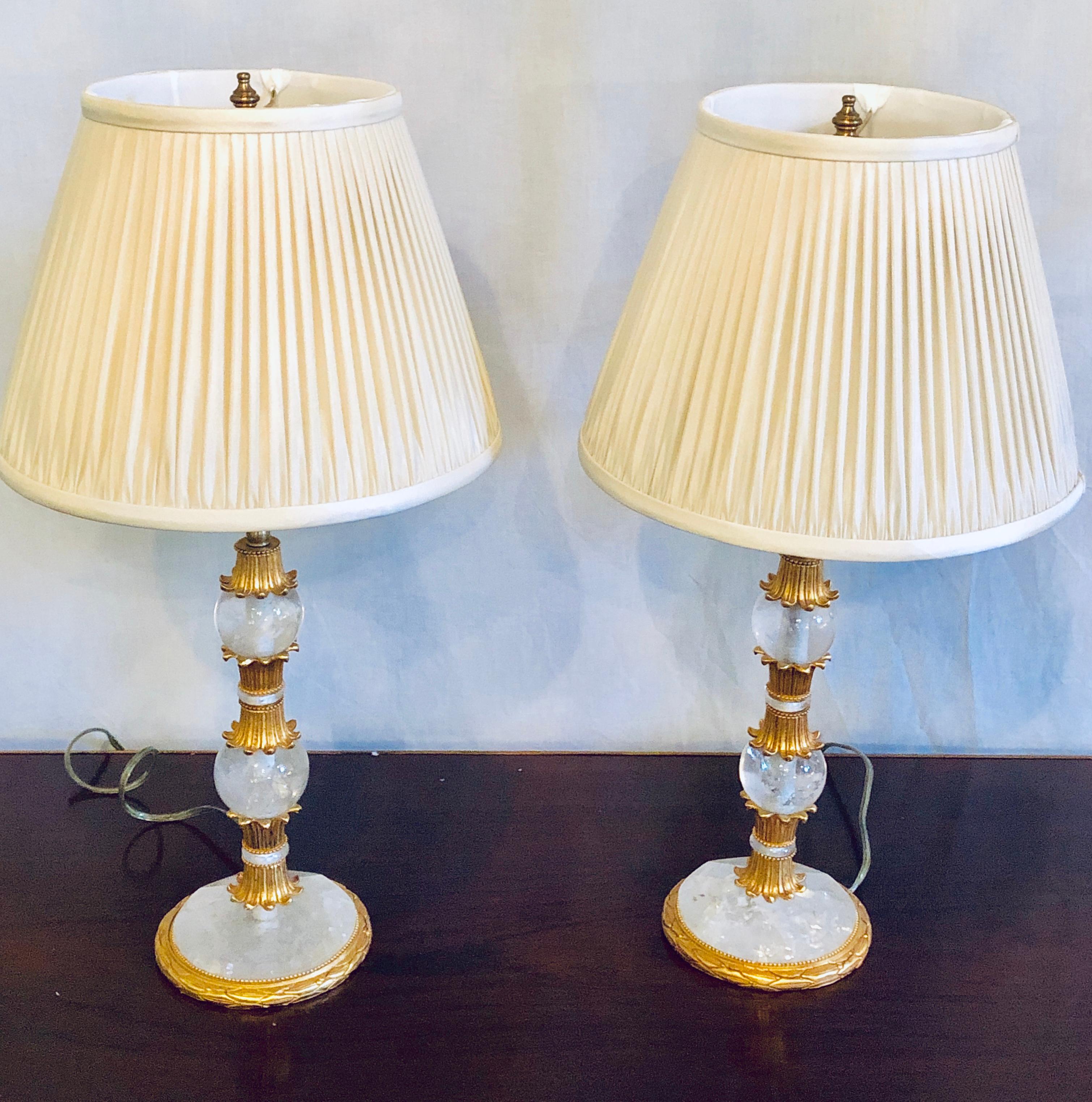 Pair of gilt metal and rock crystal Baguès style table lamps. Each having been recently rewired and with custom lamp shades. This stunning pair acquired directly from a Greenwich CT Mansion. The pair having stunning metal work with wonderful rock