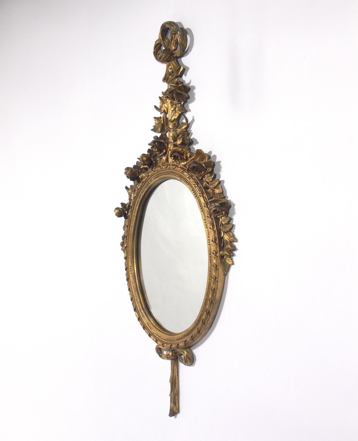 Pair of gilt oval mirrors, probably French, circa 1940s, possibly earlier. They retain their warm original patina to both the giltwood frames and the original mirrored glass.