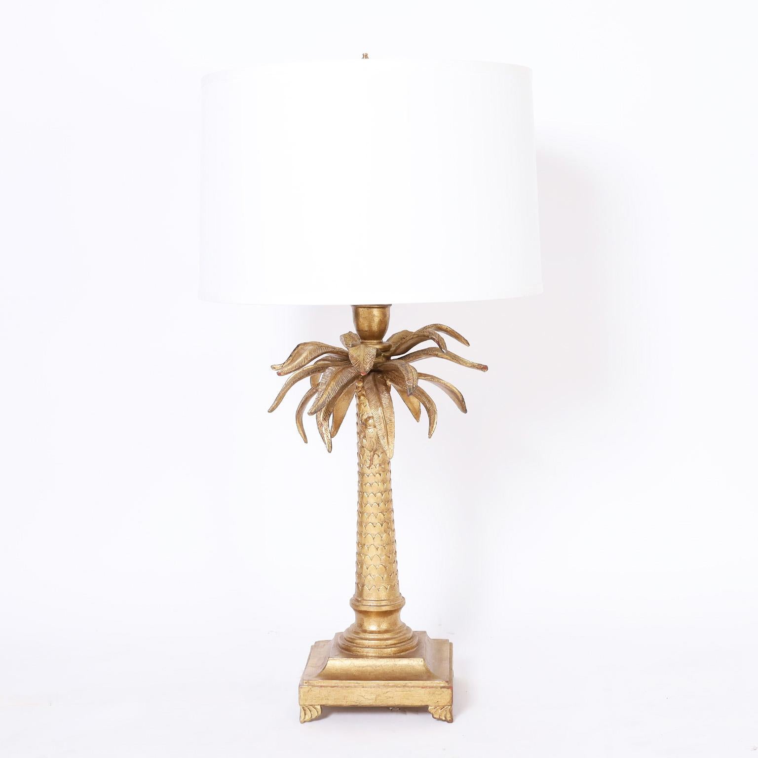 Pair of mid century regency style palm tree table lamps crafted in wood and composition in a classic form having a worn gold gilt finish with slightly exposed red primer.