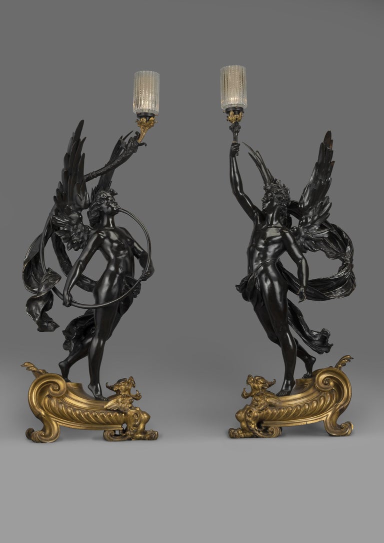 A striking pair of gilt and patinated bronze figural torcheres, by Bouchon, Paris.

French, circa 1900. 

Stamped 'BOUCHON PARIS'.

Each modelled as a winged male and female figure holding aloft a candelabra, on gilt-bronze griffin bases.