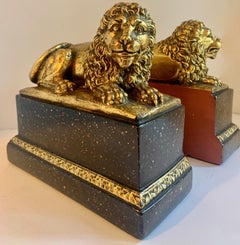 Pair of Gilt Reclining Lions on Black Stands