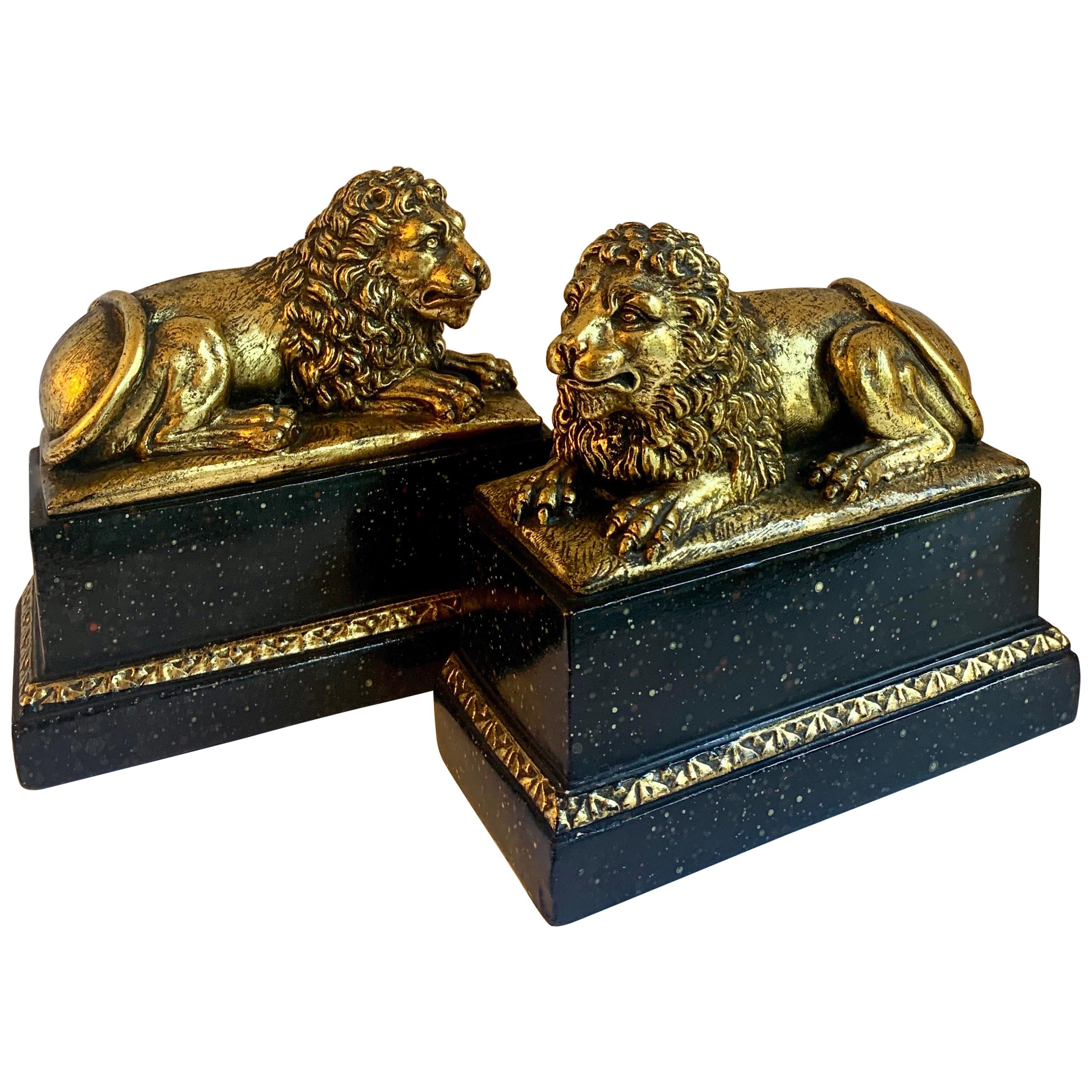 Pair of Gilt Reclining Lions on Black Stands