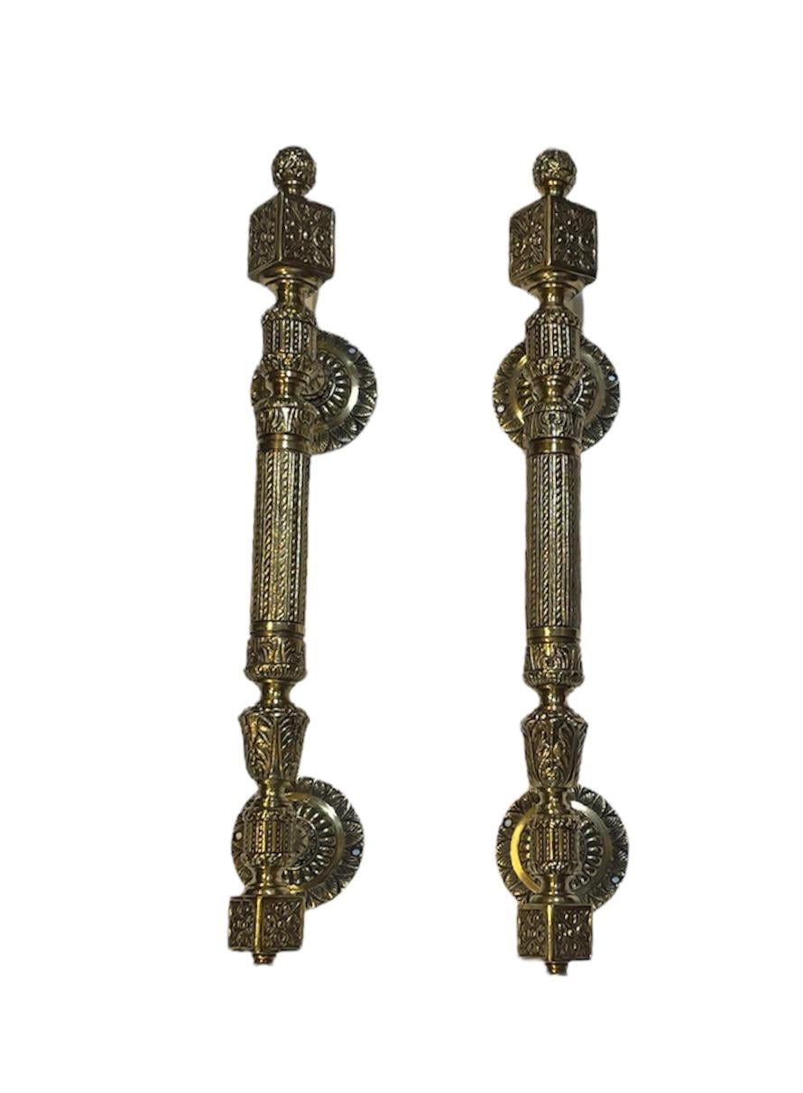 This is a pair of heavy solid bronze door pull handles. They are designed with small sphere adorned with flowers at the top followed by a cube embellished by a fleur de lis motif. Then come a baluster shaped structure decorated with beads and kind
