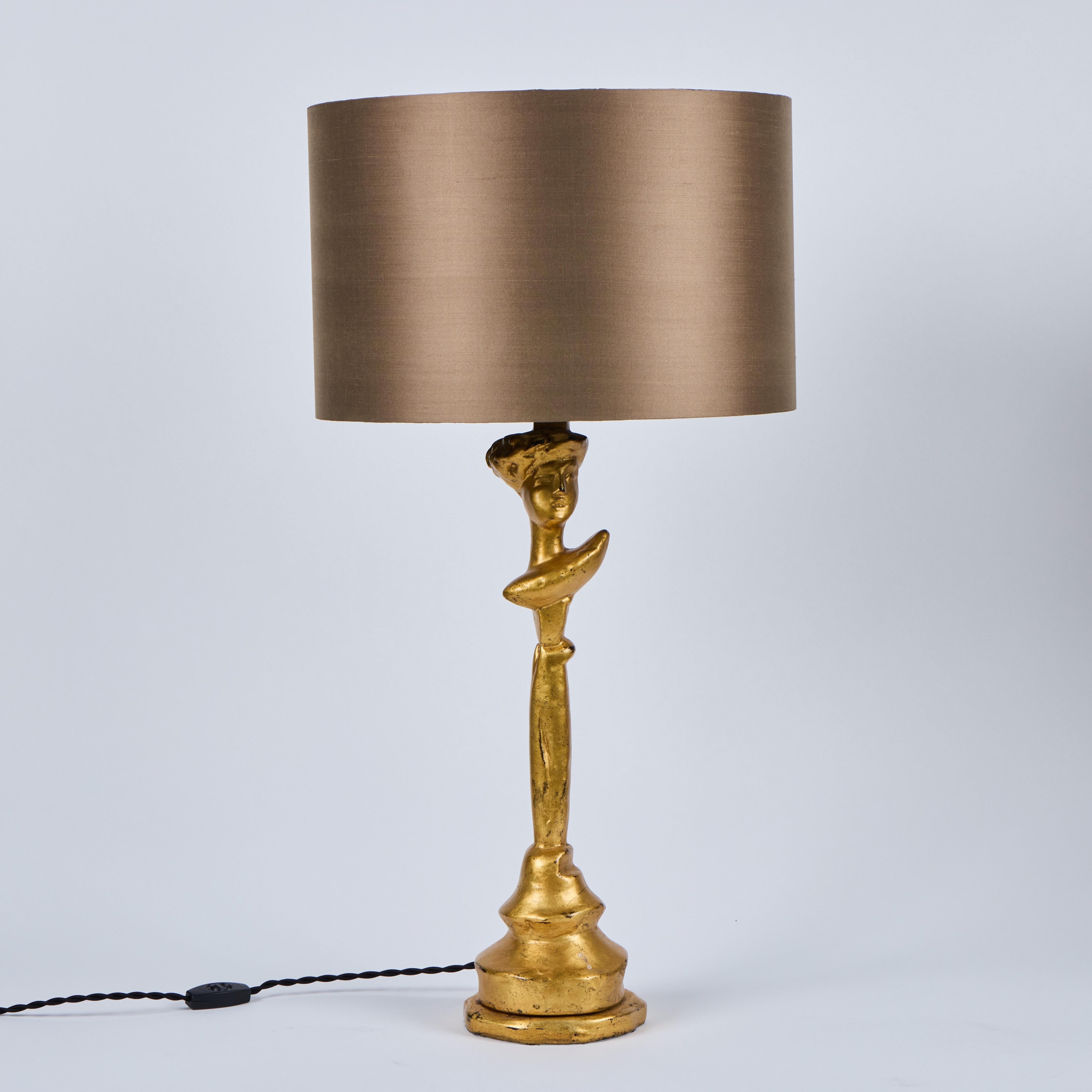 Chic pair of gilt over plaster figural lamps by Sirmos, 1980's, in the style of Giacometti.  Lamps have been newly rewired and have the Sirmos label affixed to the bottom of the lamps.  New pair of custom Dupioni silk lampshades available for