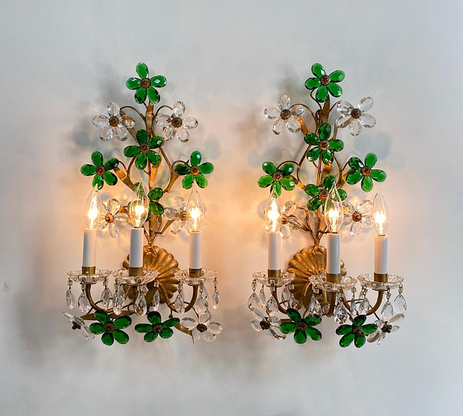 Here is a lovely pair of gilt tole sconces with clear and emerald green crystal drops attributed to Maison Bagués. Each sconce has three lights--the candle sleeves have been recently replaced.

The sconces are in very good condition--there are no