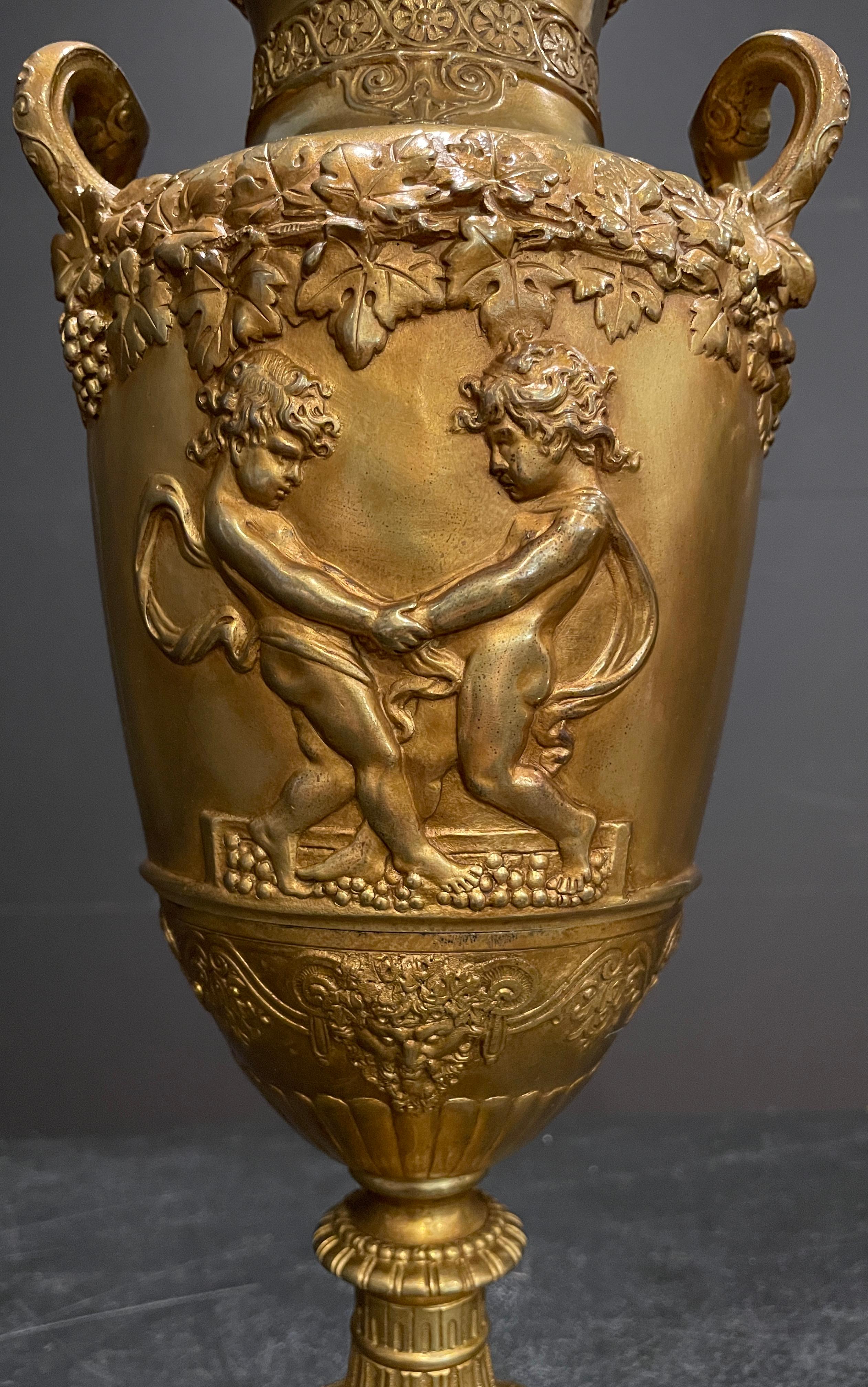 Pair 19th century French gilt bronze urns mounted as lamps. Modeled after Clodion in the Neoclassical style with grape vines, harvesting children and Bacchus masks. Mounted on green marble bases.
21
