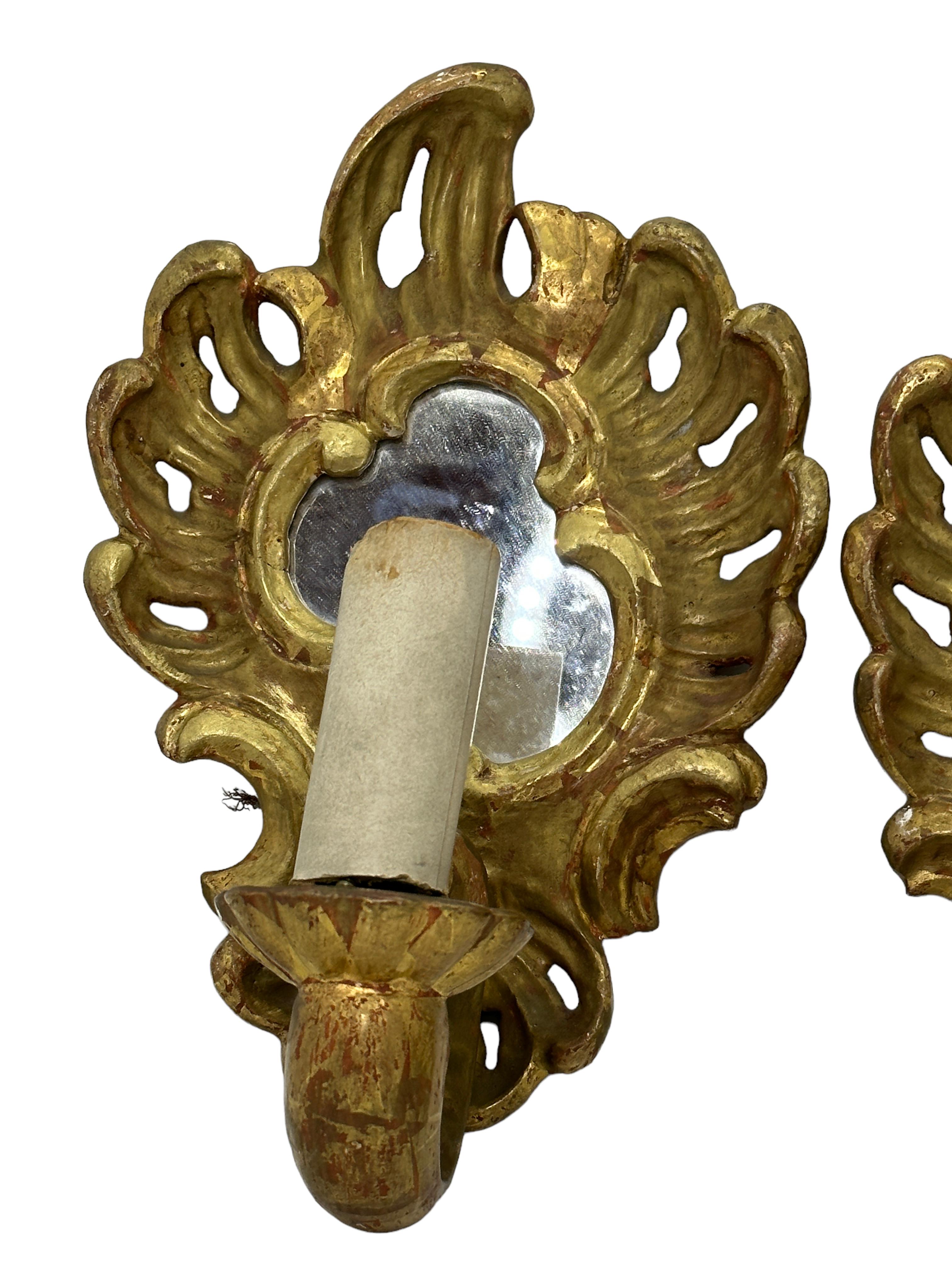 Add a touch of opulence to your home with this charming pair of sconces. Perfect gilt wood and a mirror to enhance any chic or eclectic home. We'd love to see it hanging in an entryway as a charming welcome home. Built in the 1920s, in Italy, these