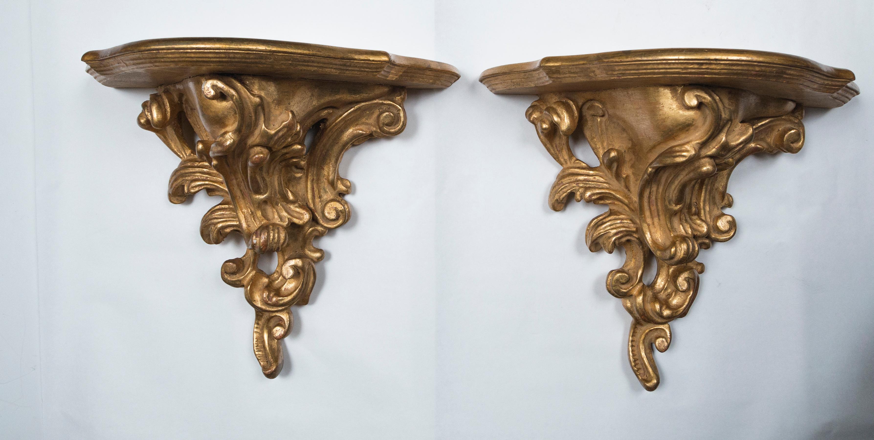 Dating from the 19th century, this pair retains their original gilt over gesso. There is a piece of gilting on the top rear left edge, measuring 1.75 x 1/2 inch. And just down to the wood. Deeply carved dramatic rococco swirls. Shaped shelf. The