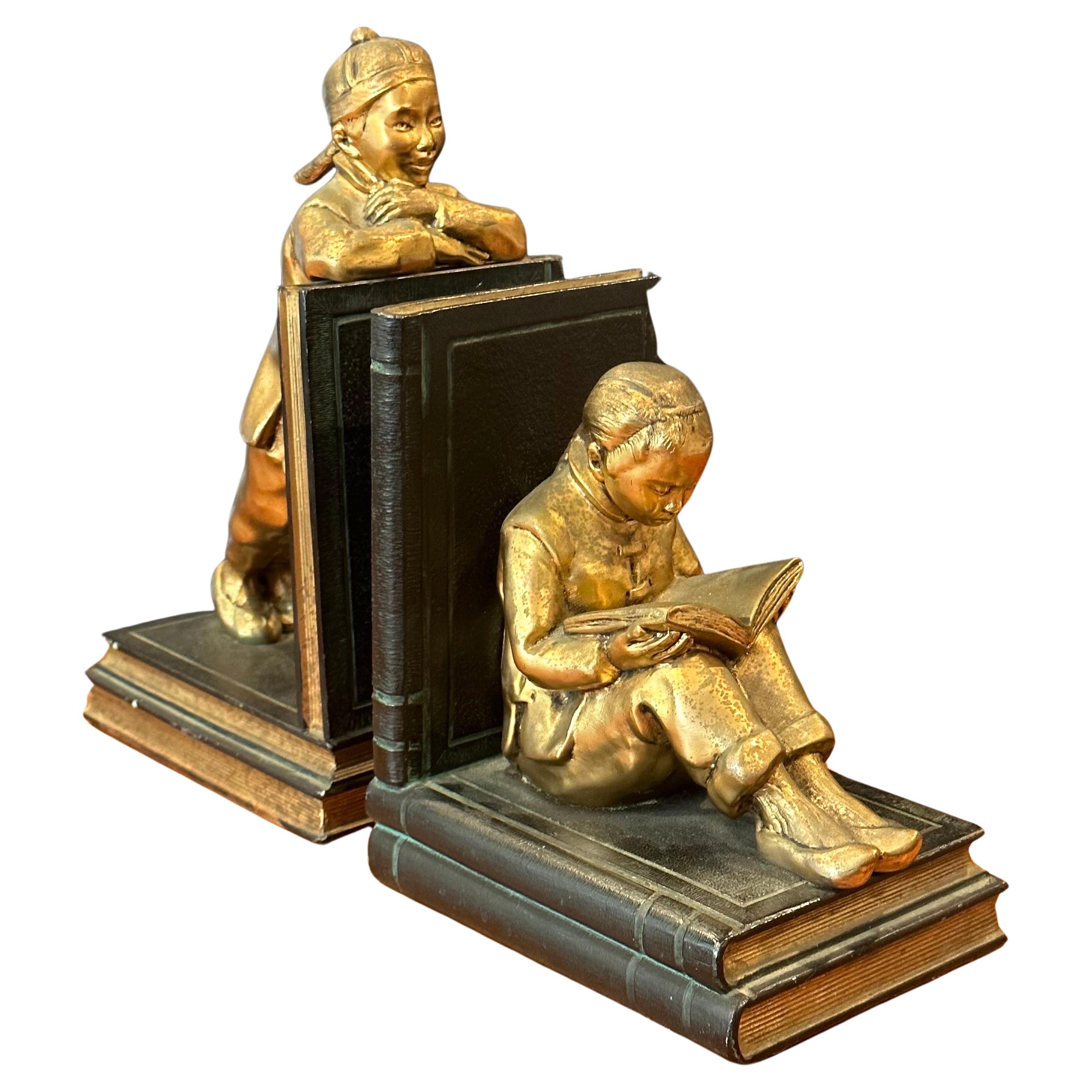 A fabulous vintage pair of gilted metal clad Chinese children scholar bookends by Ronson Art Metal Works, circa 1930s. The bookends depict two Chinese youngsters, beautifully sculpted; the boy is patiently observing while the girl is quietly
