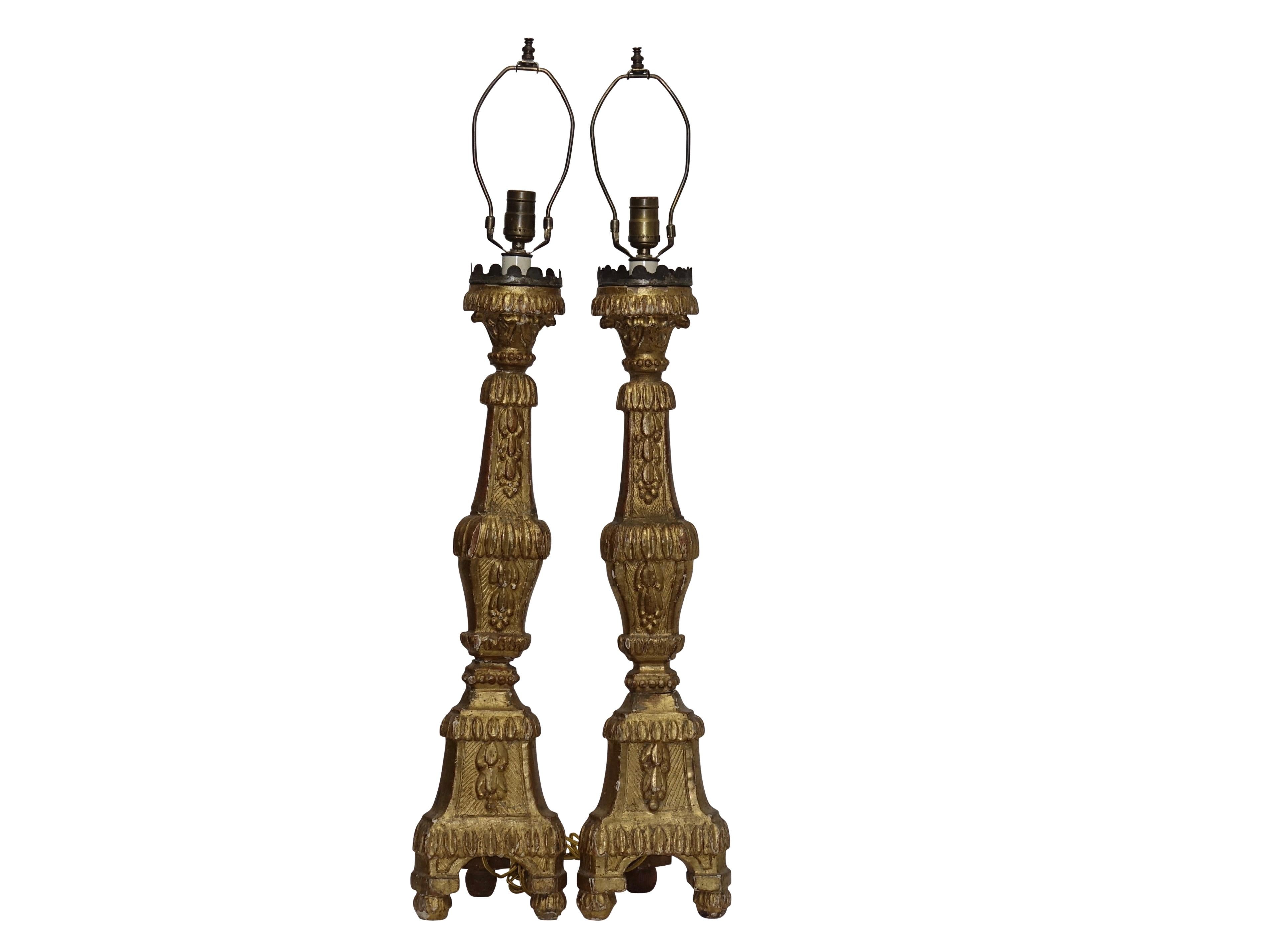 A pair of carved and giltwood altar candle sticks with tin cups having a scallop rim, now electrified as lamps. Recently re-wired. Italy, 18th century.
Height measurement to the top of the socket is 31 inches.