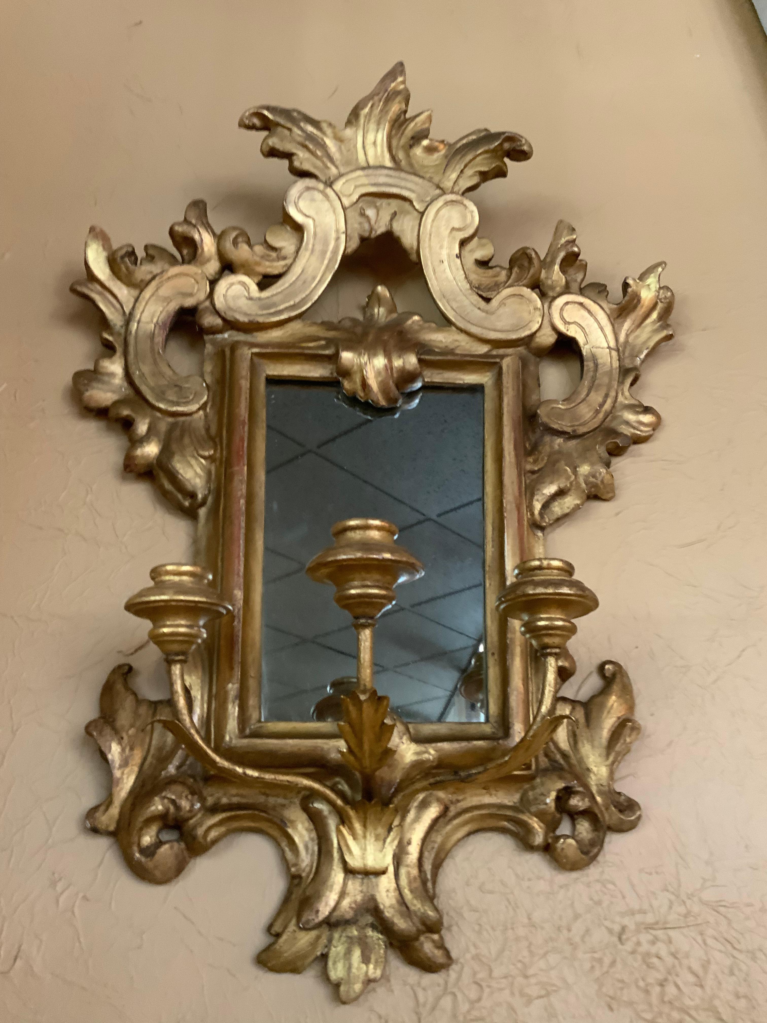 Appliques in legno dorato splendidamente intagliate con design a volute, ciascuna delle quali sostiene 
Braccia per tre candele. Schienale a specchio.