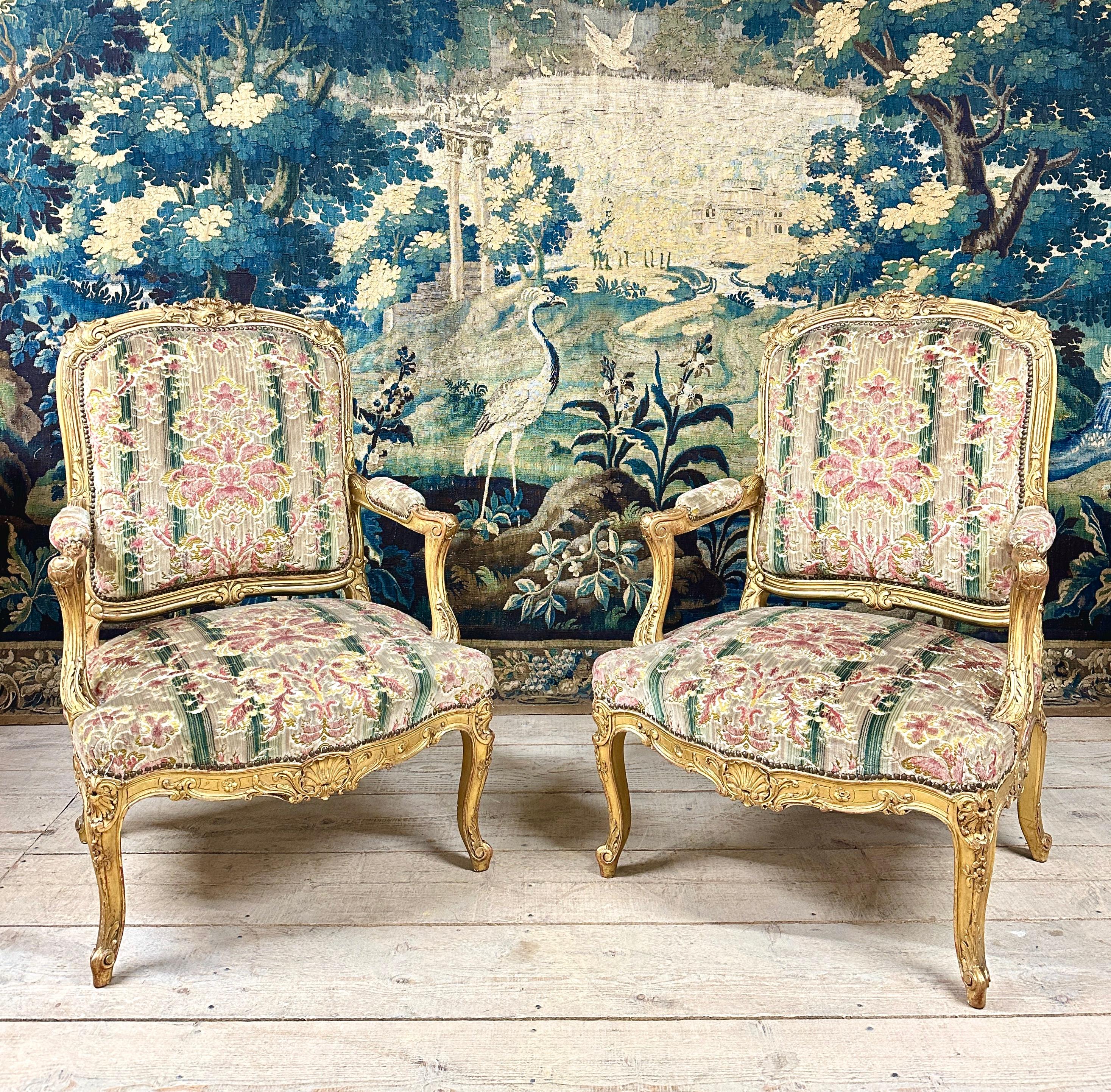 Pair of richly carved giltwood armchairs in the style of Jean-Baptiste Tilliard, famous 18th century cabinetmaker active under Louis XV, a very similar model of which is kept at the MET museum. Work in gilded wood with 19th century Napoleon III