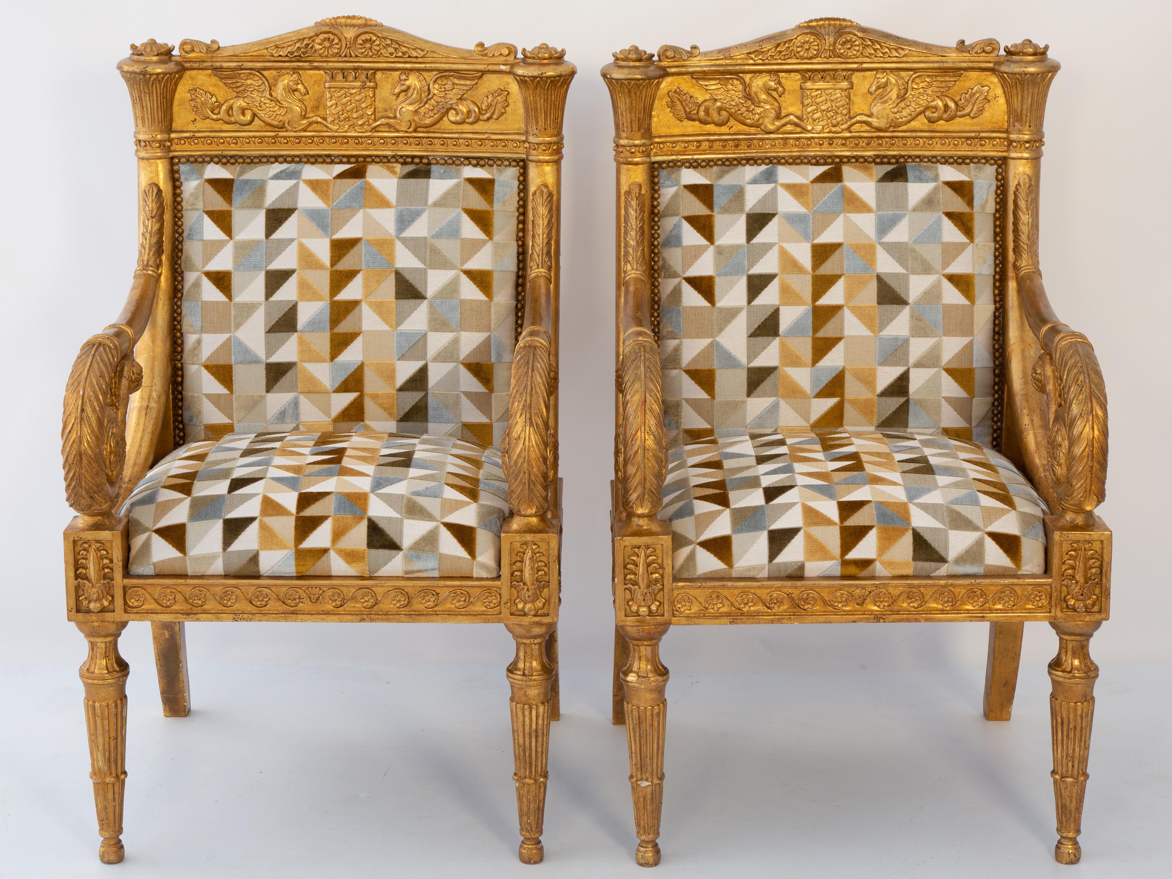 Une paire de fauteuils en bois doré de style baroque et néoclassique, dont les cadres sont sculptés de motifs classiques. Les crêtes élaborées sont ornées de serpents de cheval ailés, reprenant les motifs gréco-romains, flanquant un bouclier. Les