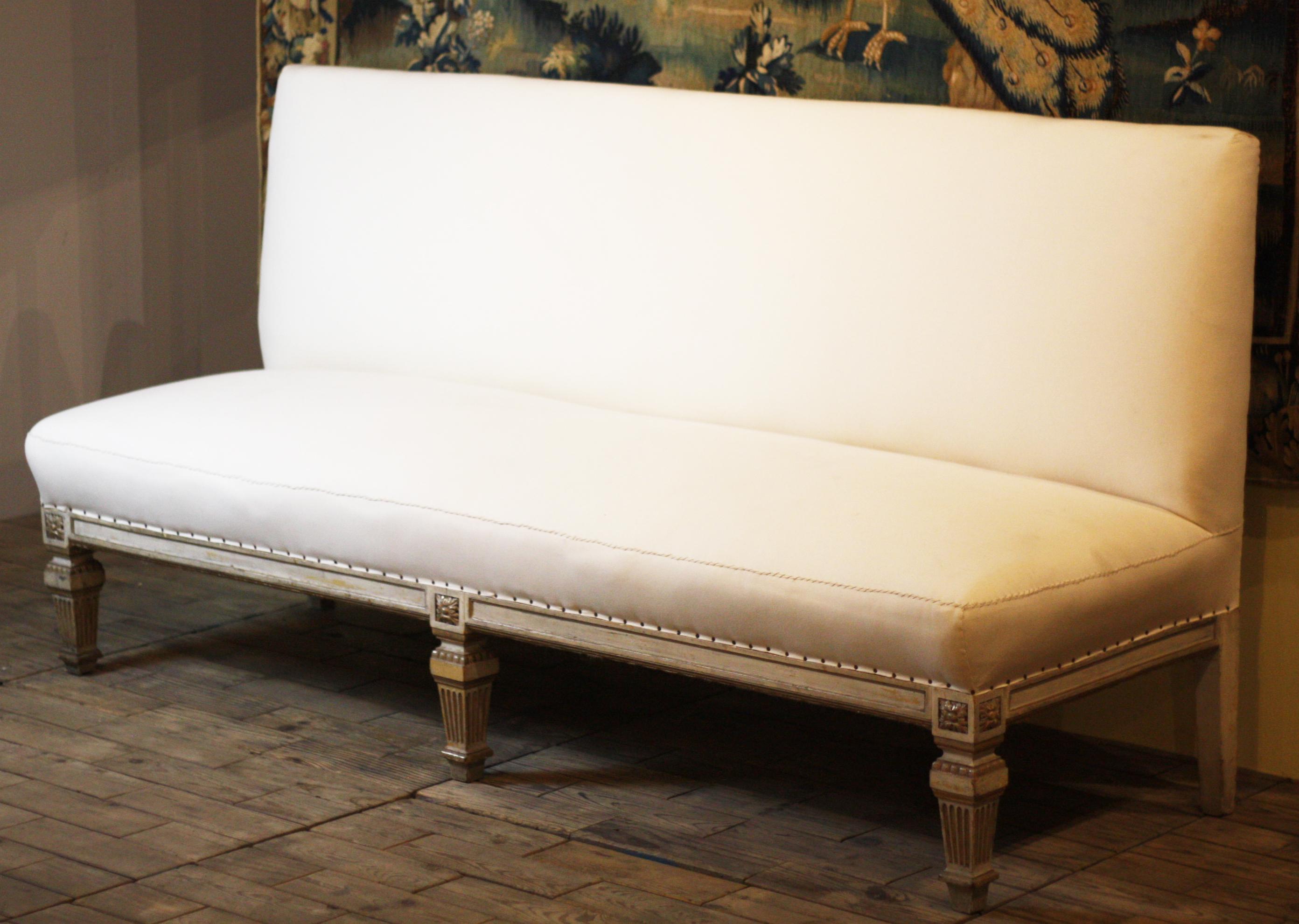 A fine pair of giltwood Louis xvi banquette canapes, carved, circa 1880, the benches are raised on six tapered legs, symmetrical carvings around the apron, and recently reupholstered in calico with decorative stitching.