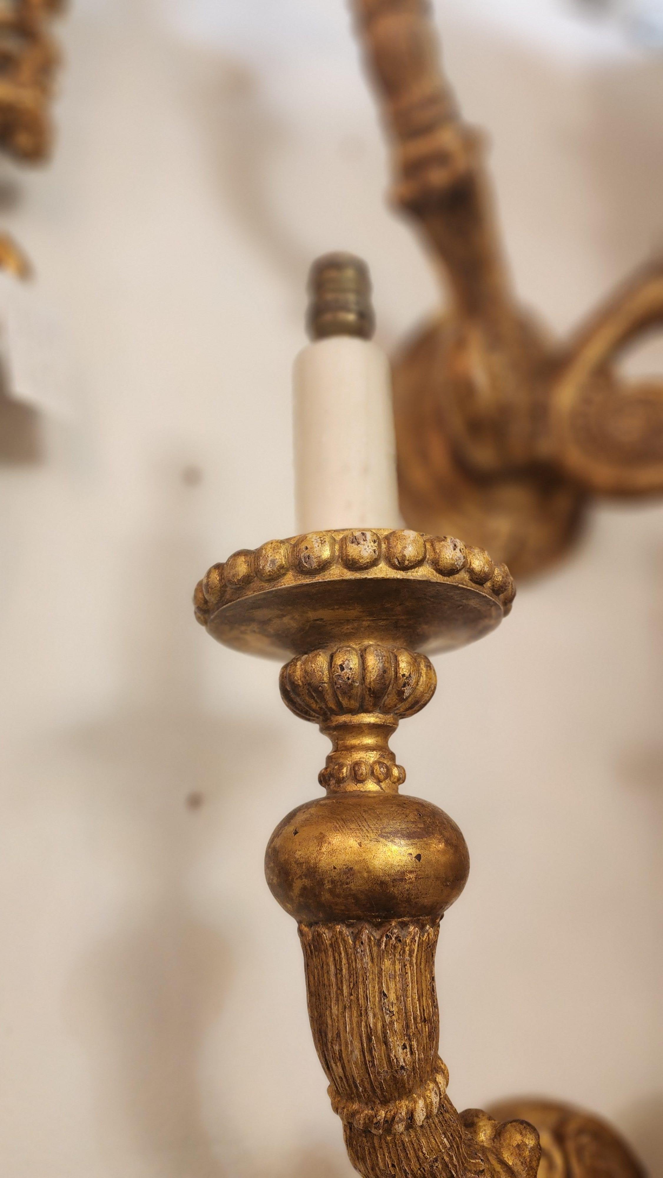 Cette paire d'appliques présente des bras sculptés qui s'incurvent vers l'extérieur, chacun étant orné de nervures, de cannelures et de rosettes classiques. Ils sont de style Louis XVI, avec une patine vieillie, ce qui renforce leur caractère.