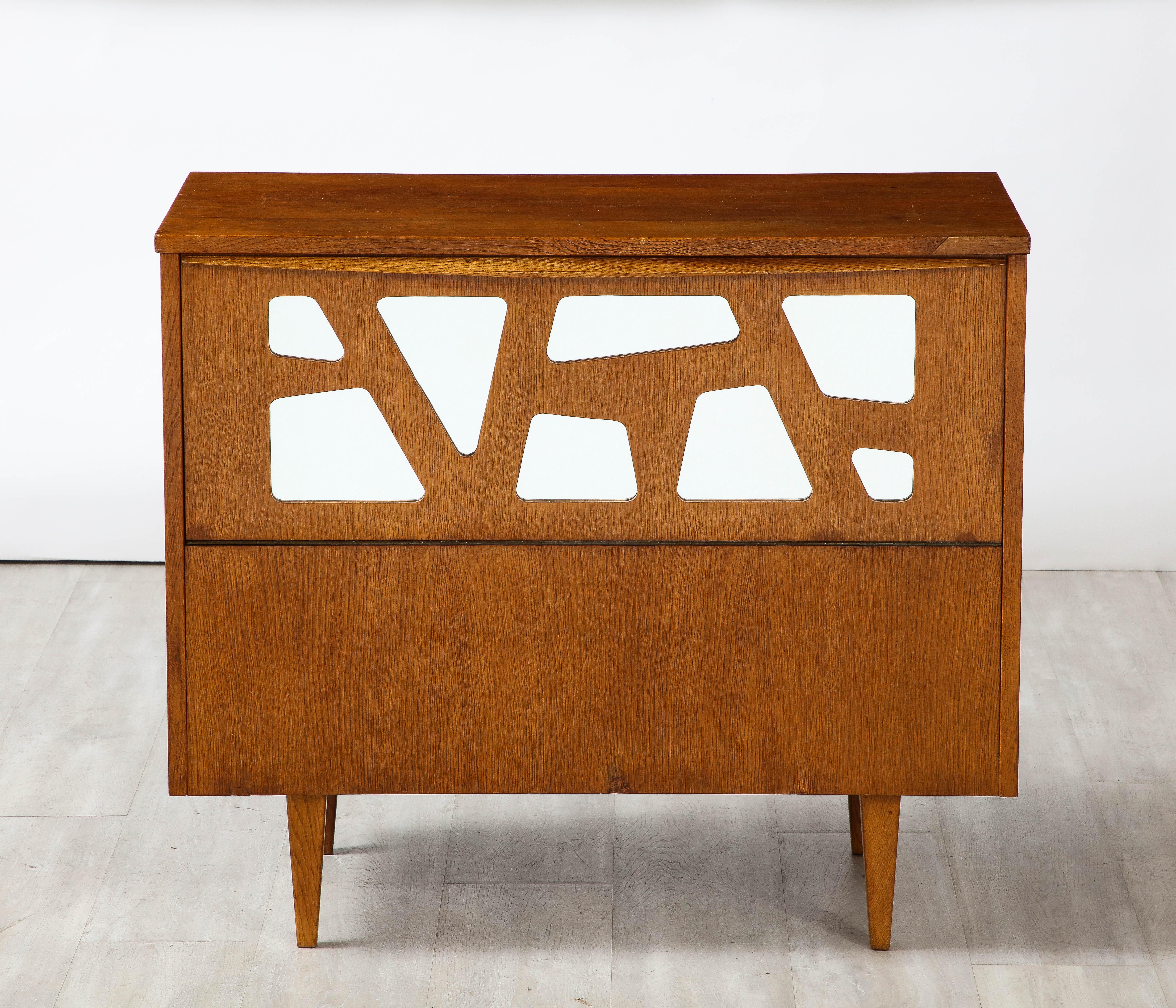A pair of Gio Ponti attributed oak cabinets, this rare and unique pair feature an upper portion which opens out and is decorated with a modernist geometric cut out motif, the geometric shapes are inset with glass. The warmth of the oak contrasts