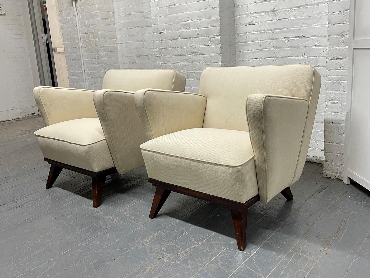 Pair of Gio Ponti style lounge chairs. The chairs have arched arms, splayed hardwood legs and upholstered in a cotton blend fabric.