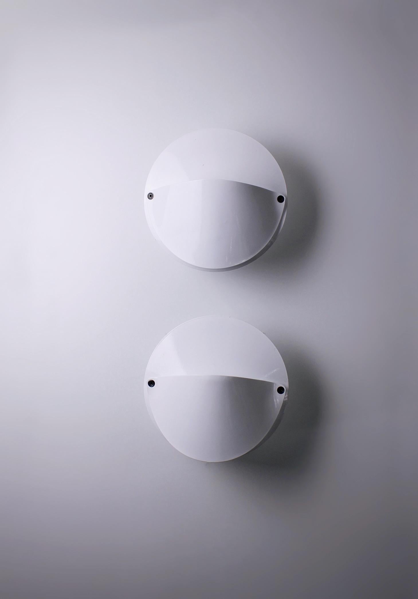 Pair of wall lamps, model Giovi. Designed by Achille Castiglioni for Flos in 1982. One of the many special designs created by Castiglioni. Fully made of white lacquered metal. The light source is covered by the white shades. Around the light source
