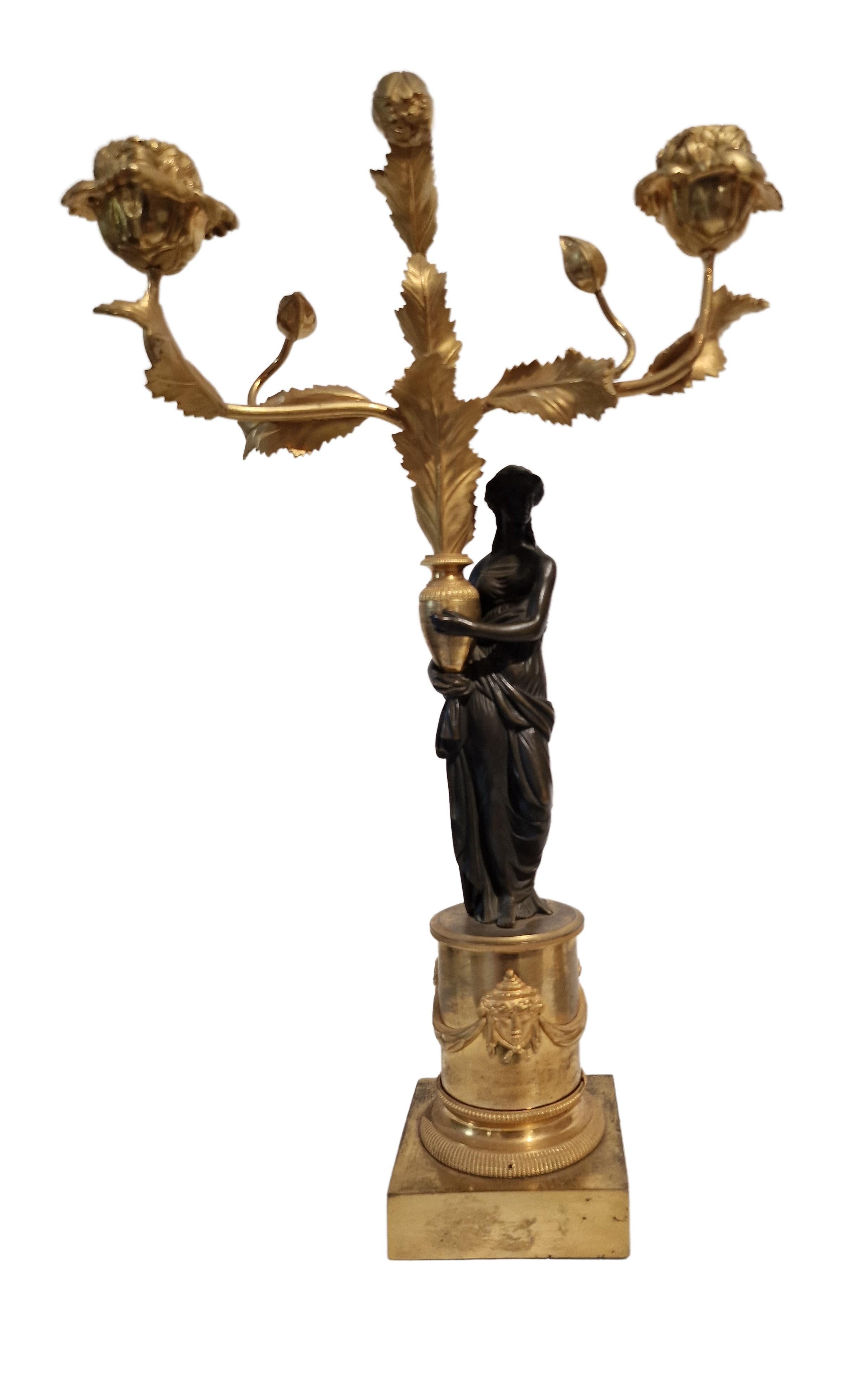 Stunning pair of so called Girandoles, made in France around 1810, in the famous Empire period. 

The stepped pedestals are beautifully designed with masks and garland décor. On each of them are an antique-style female figure made in bronze (typical