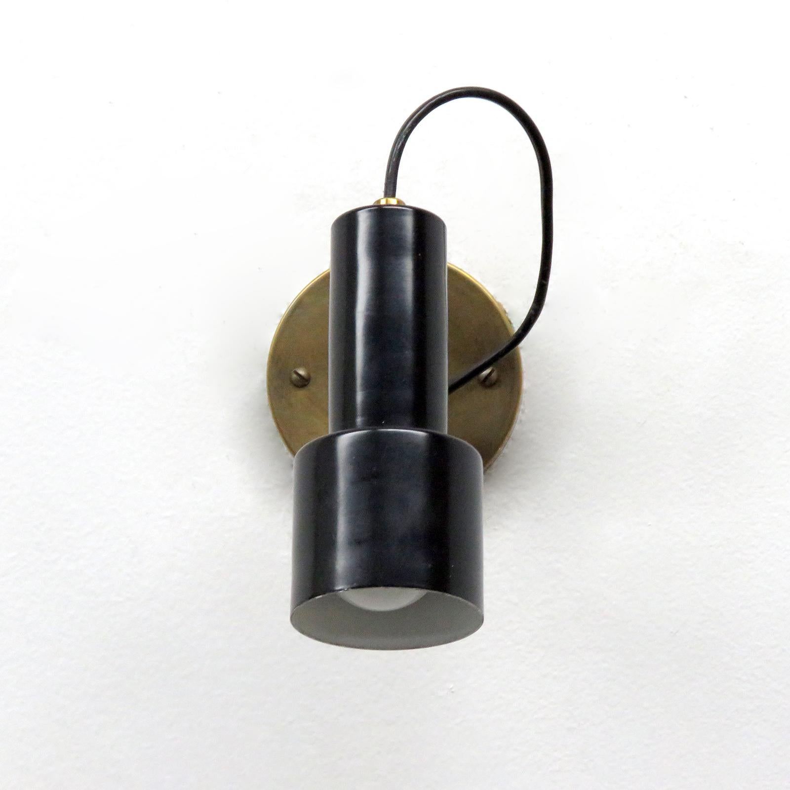 Wonderful pair of articulate wall lights by Giuseppe Ostuni for Oluce, Italy, 1950s, with black enameled bodies on a Dual-joint brass arm.