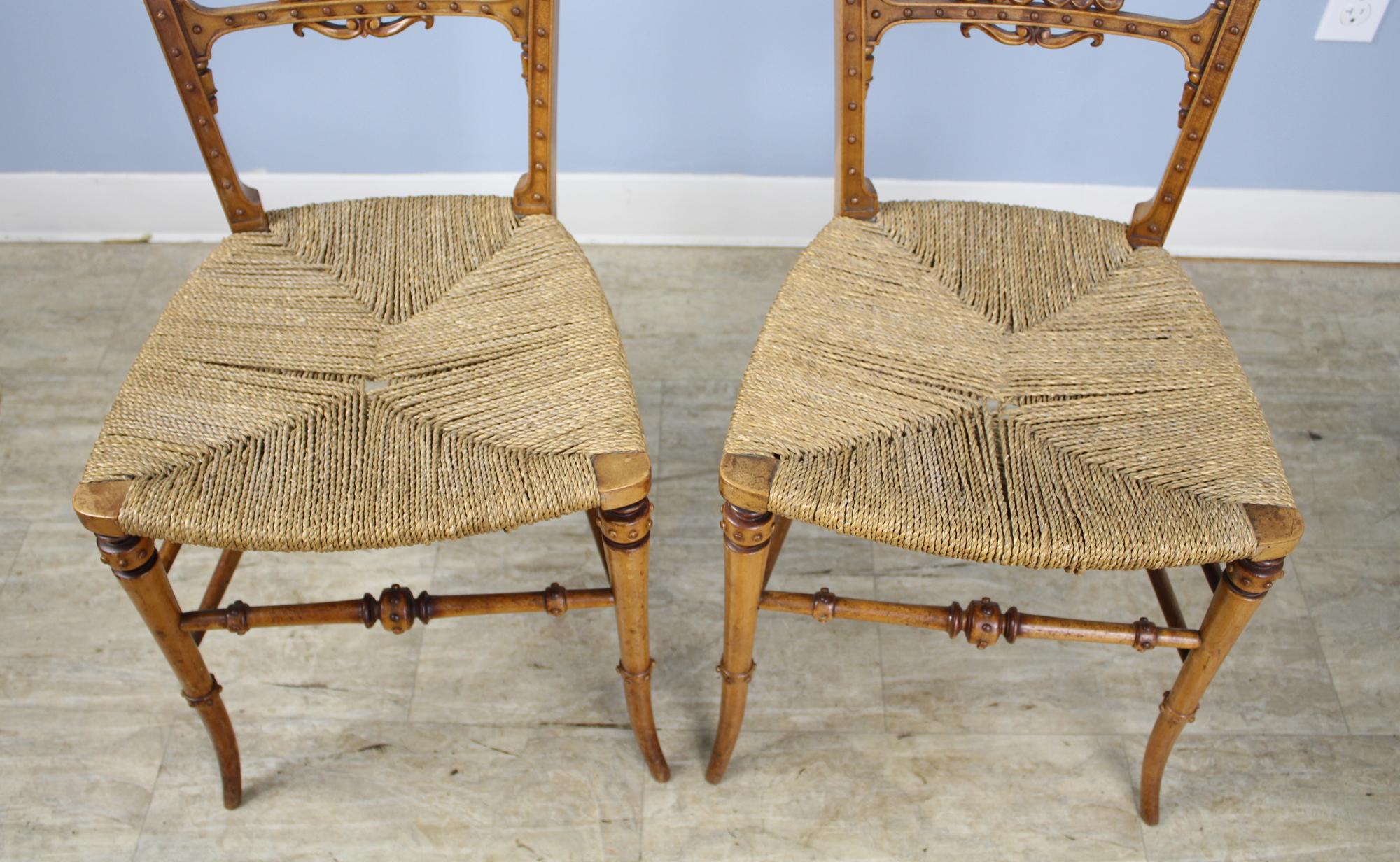 An unusually pretty pair of intricately carved German bedroom chairs. We believe them to be fashioned of yew wood. The seats, made of woven rope, are in very nice antique condition. These would be divine on either side of a chest of drawers or as