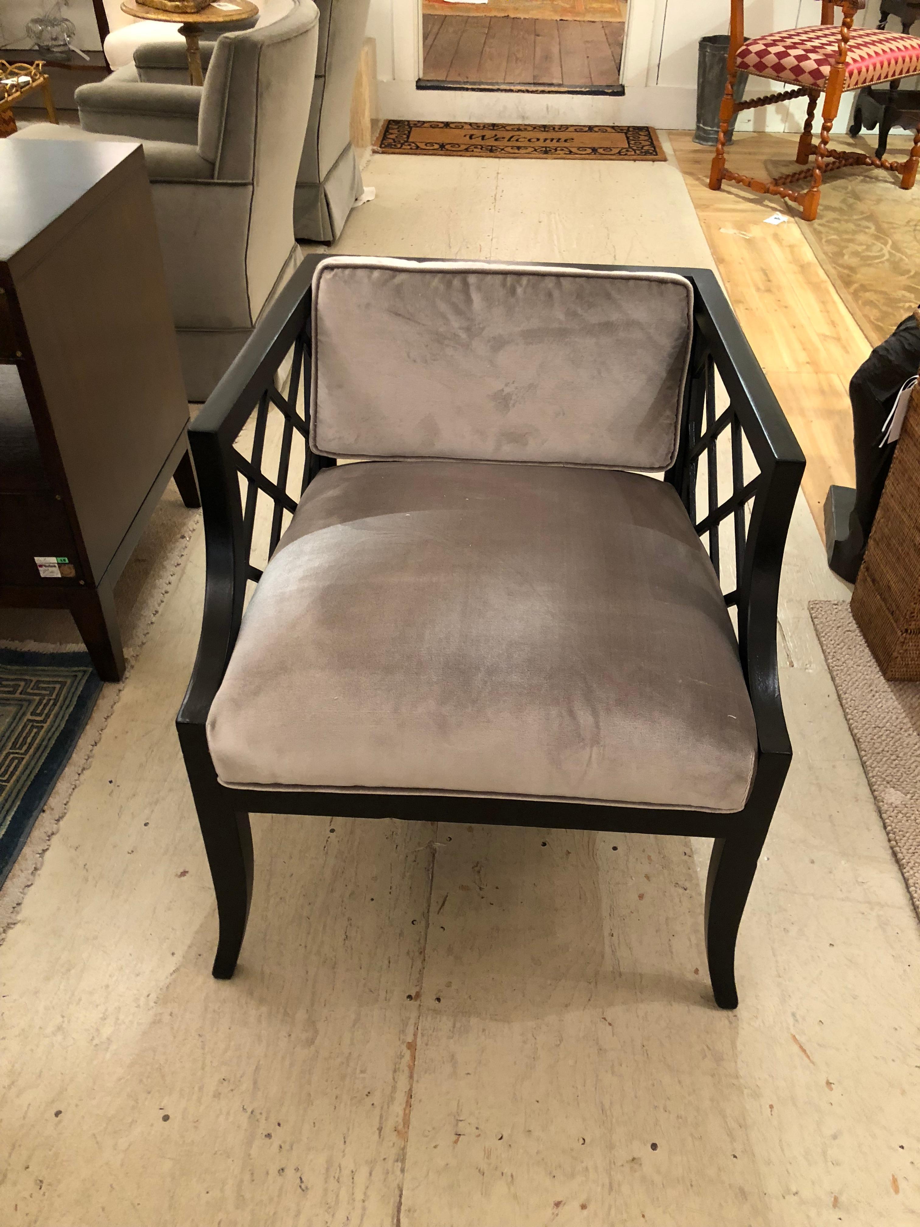 Elegant pair of midcentury Hollywood Regency chairs attributed to Baker in an ebonized finish. Chairs are of a substantial weight and have been newly upholstered in a platinum pale grey cotton velvet. Back cushion is loose; fretwork on back and