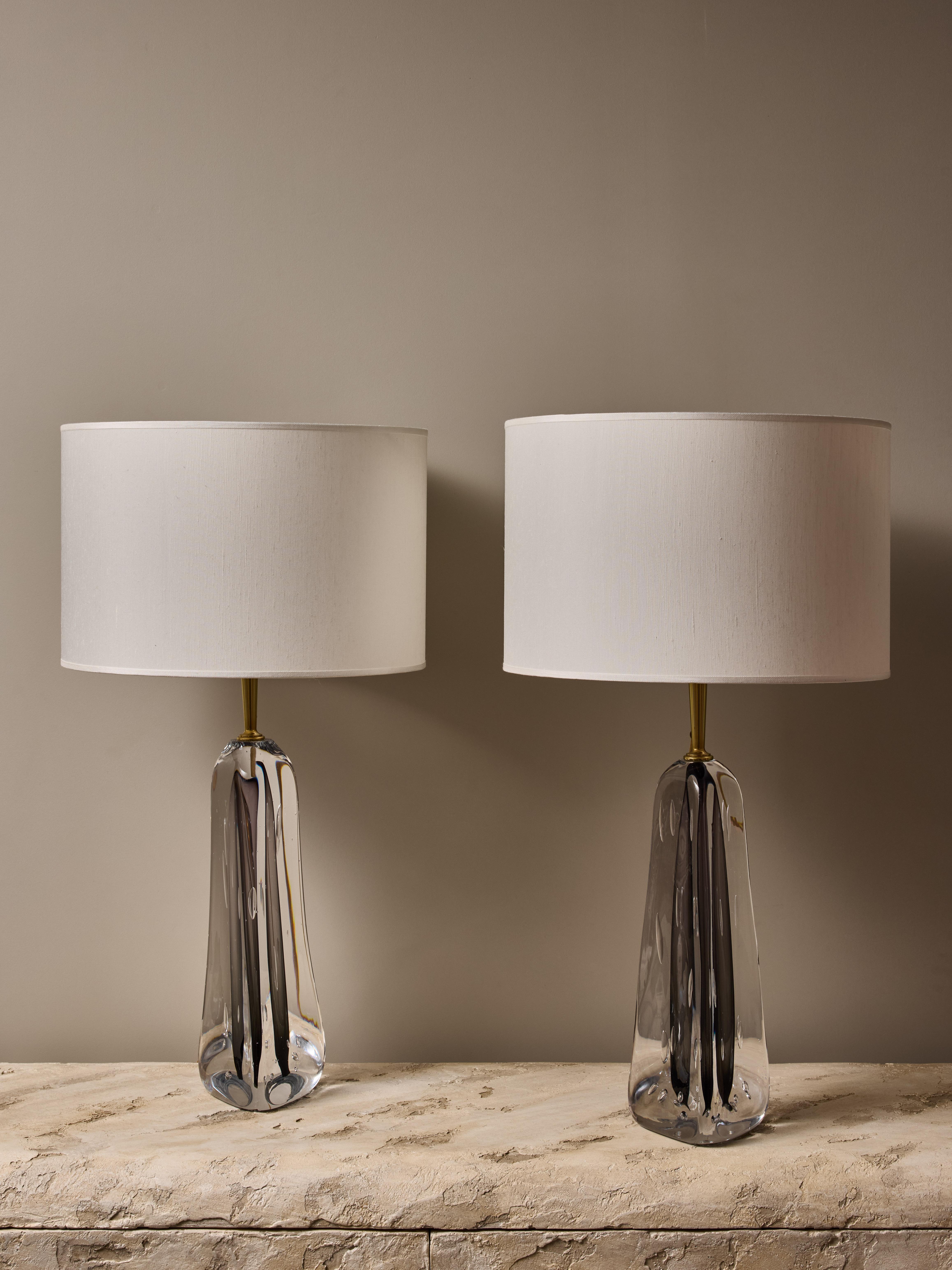 Pair of table lamps made by Esperia, each made of a triangular foot in blown clear glass, with a streak of dark grey in the center. Some air bubbles are visible in the glass, which is topped with a polished brass stem holding two sources of light