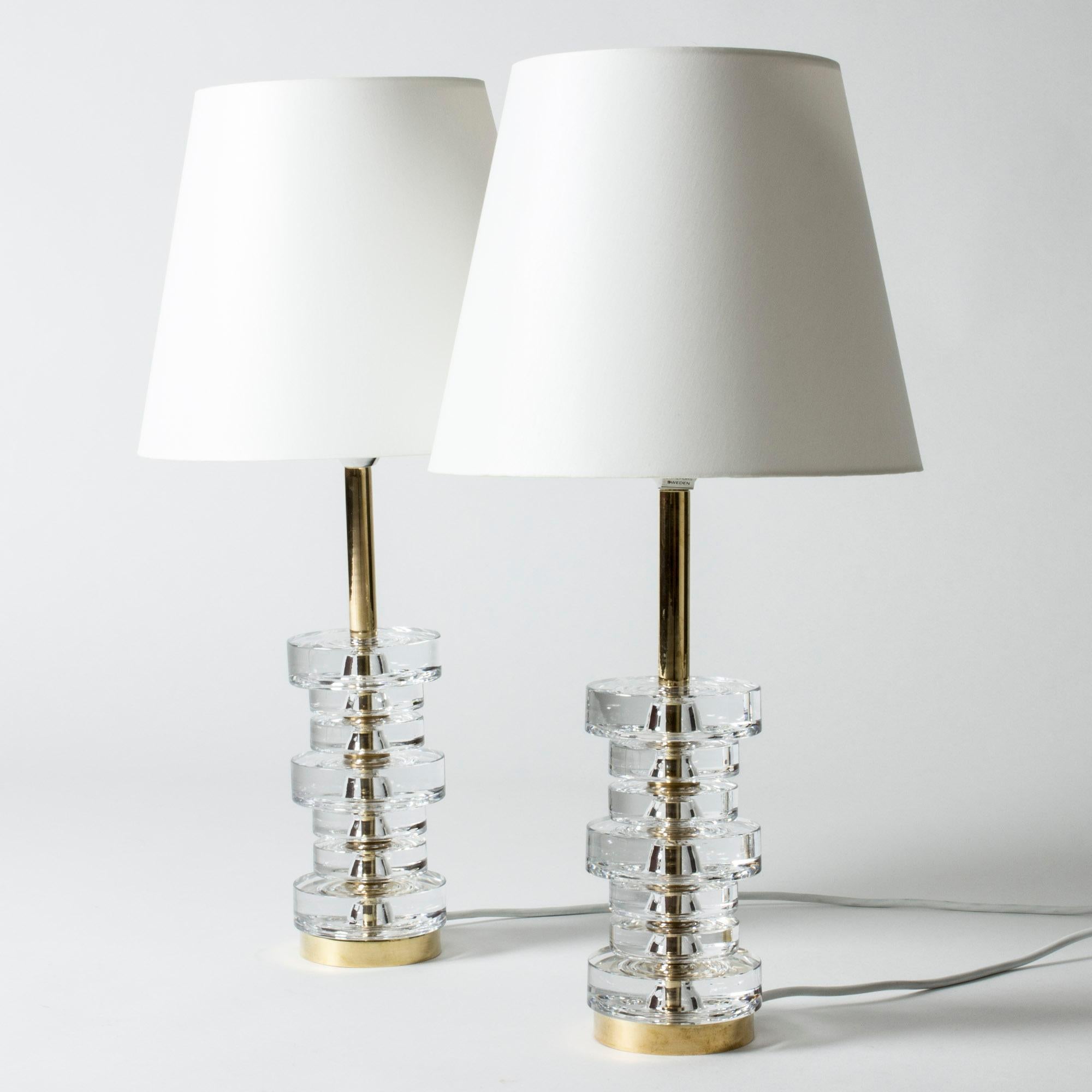 Pair of elegant table lamps by Carl Fagerlund, made in crystal glass and brass. Bases made from thick, clear stacked crystal discs around a brass center bar.